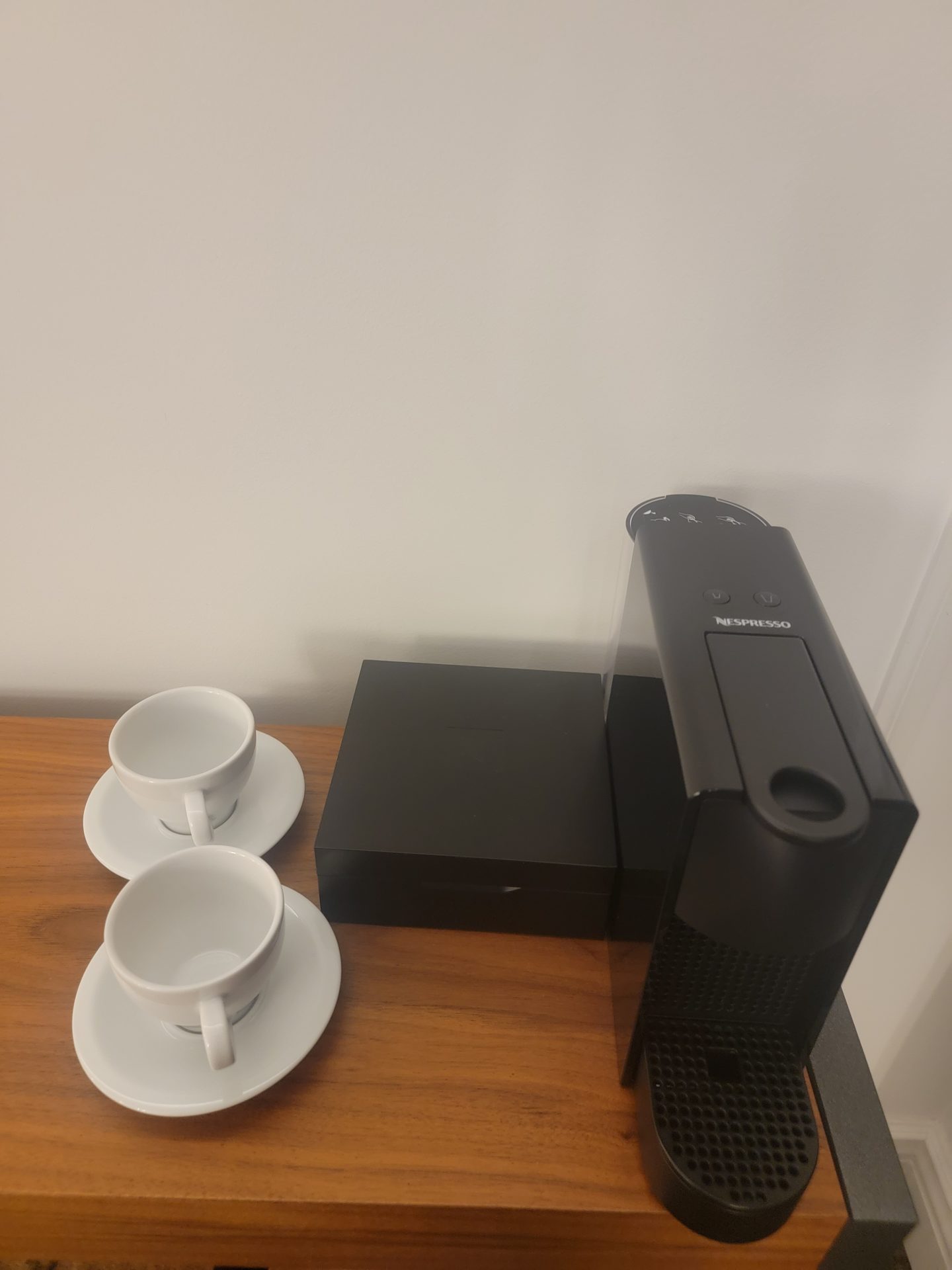 a black computer and two white cups on a wooden surface