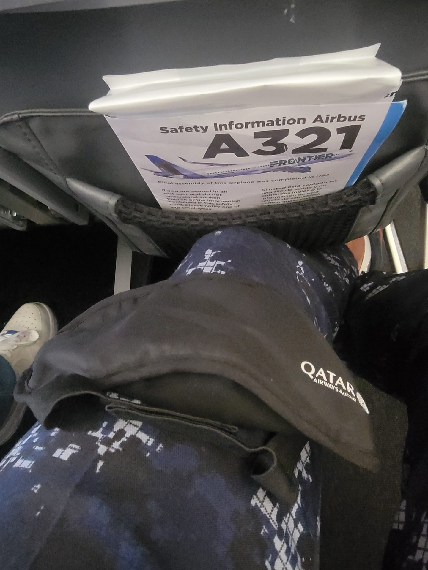 a person's leg with a safety information on the back of a seat