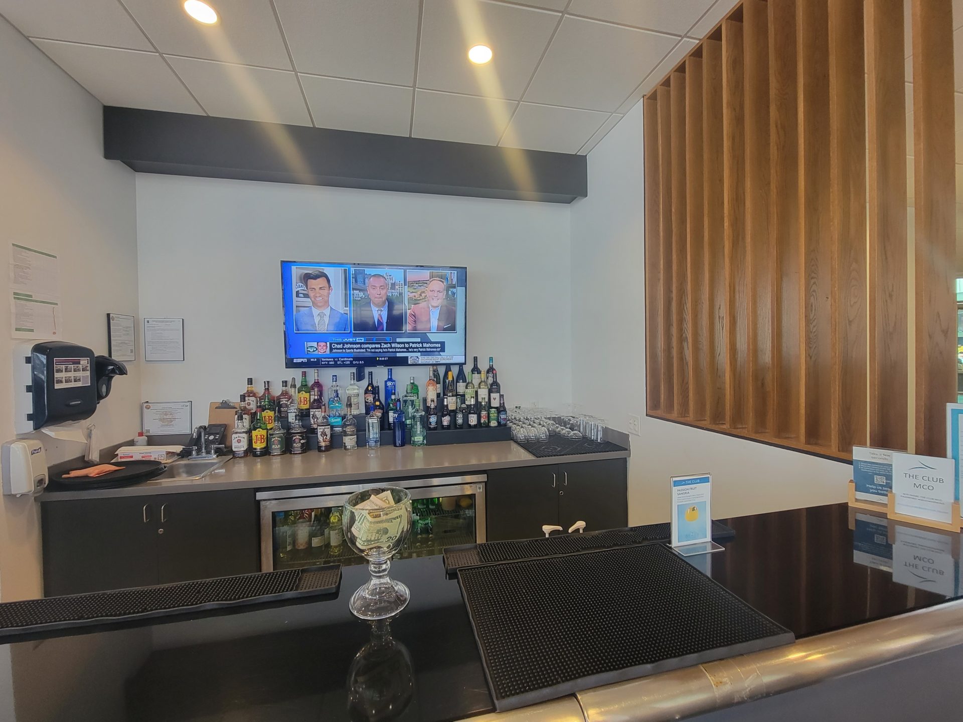 a bar with a television and bottles on the wall
