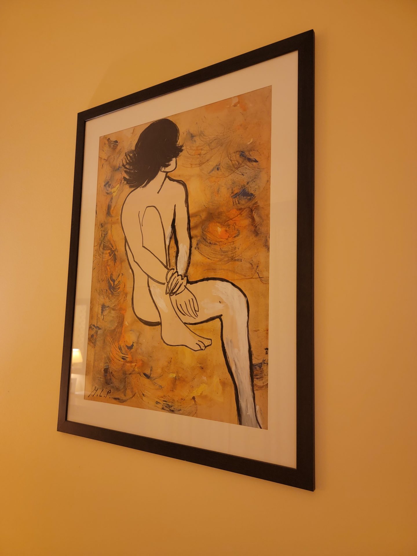 a framed picture of a woman sitting on a tan wall