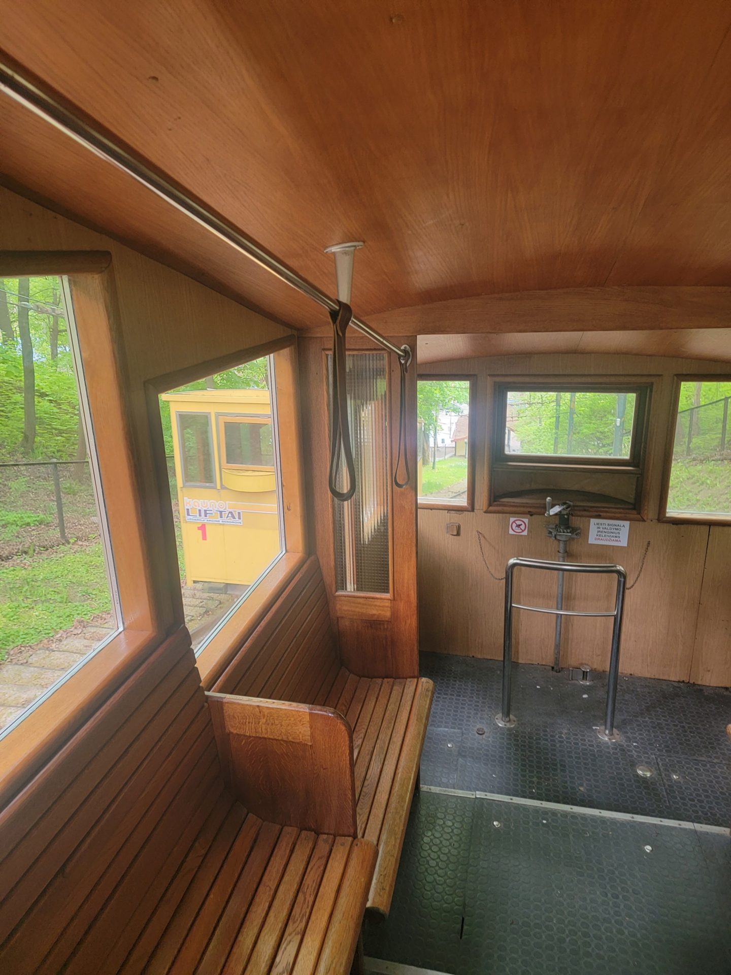inside a wooden train with a bench and a metal bar