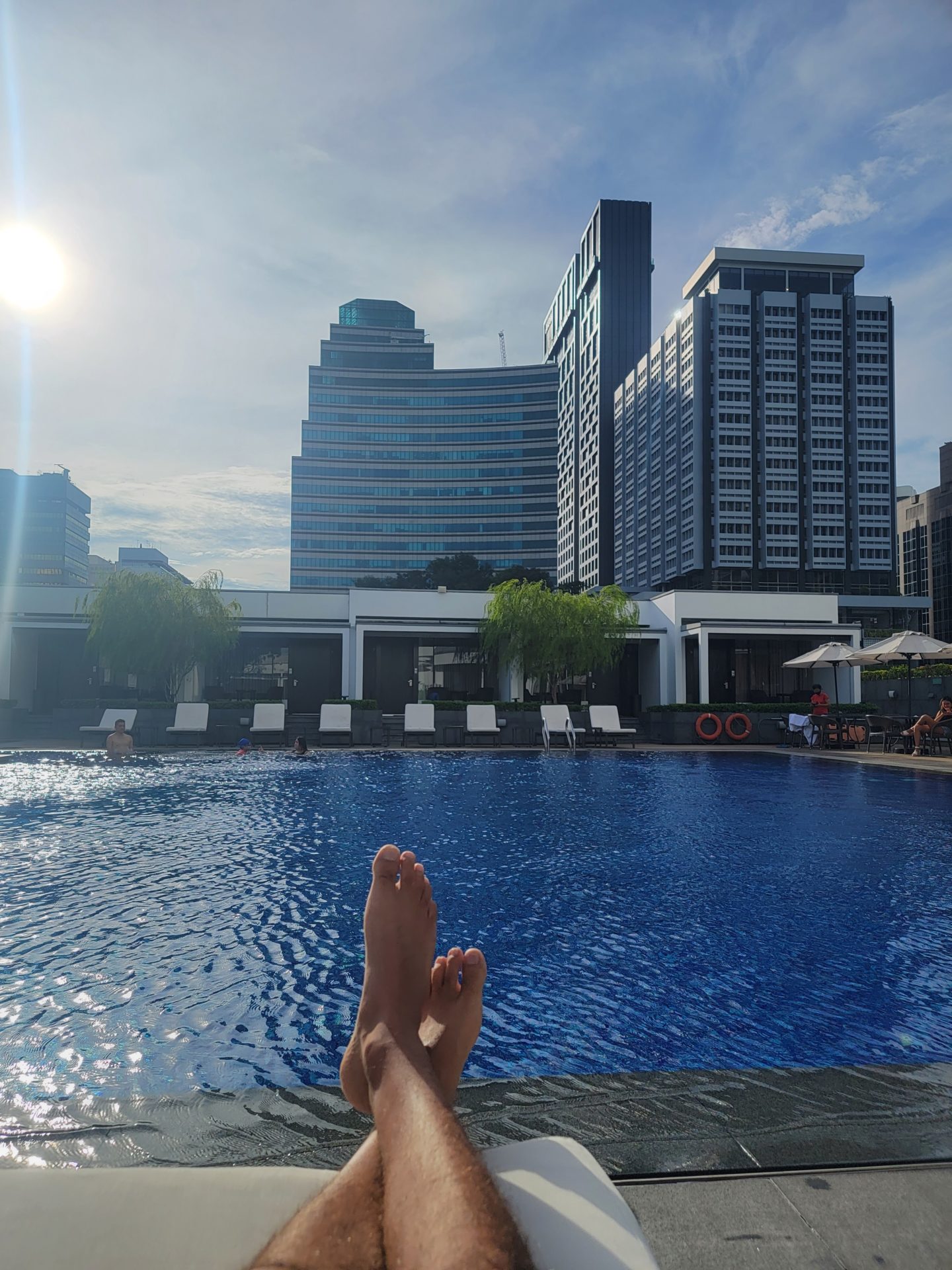 a person's feet in front of a pool with buildings in the background