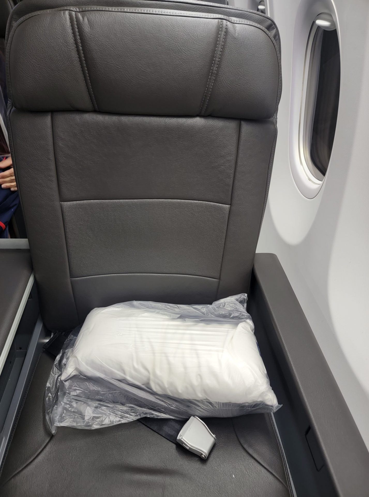a white pillow in a plastic bag on a seat of an airplane