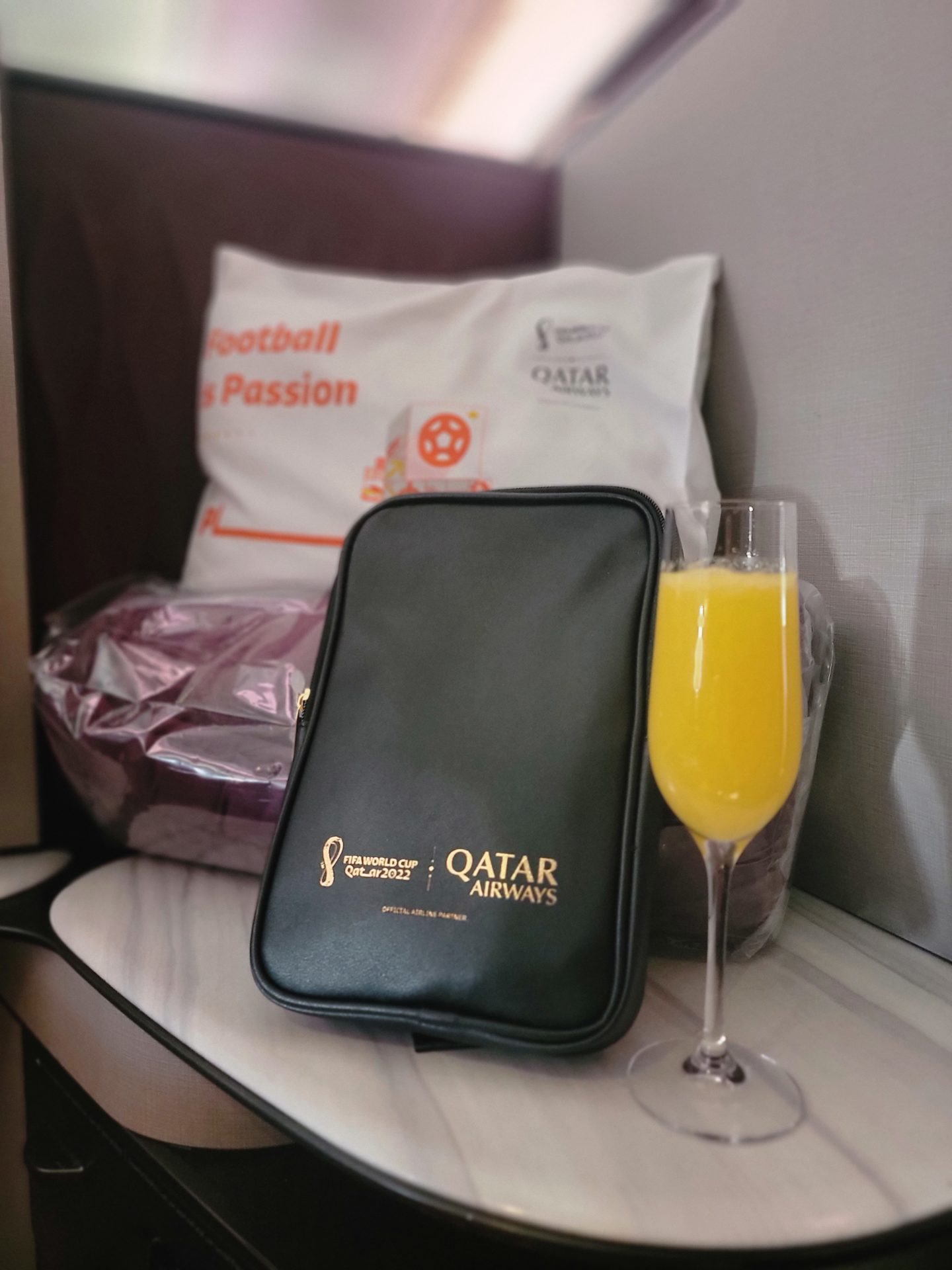 a black bag and a glass of orange juice next to a bag