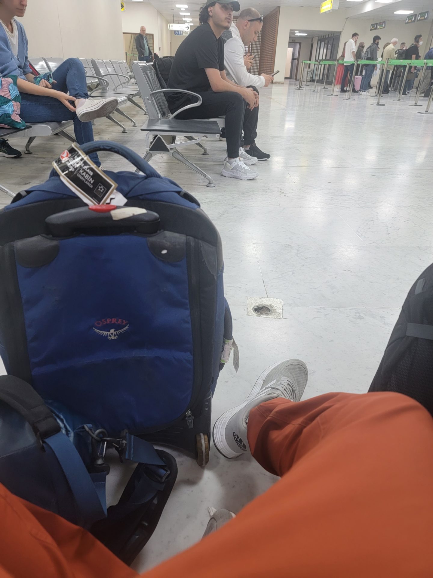 a group of people sitting in chairs and a blue suitcase
