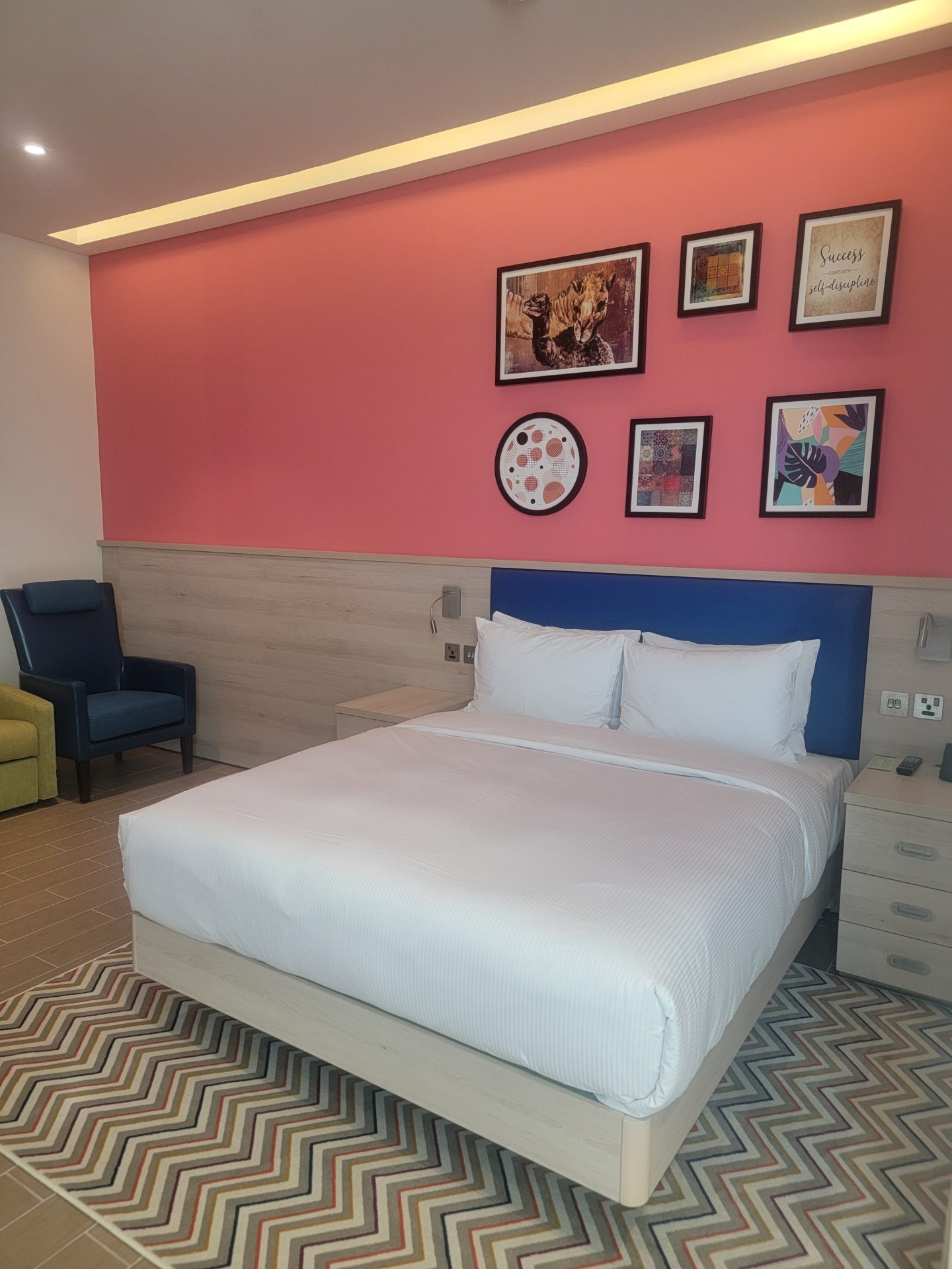 a bed in a room with pink walls and pictures on the wall