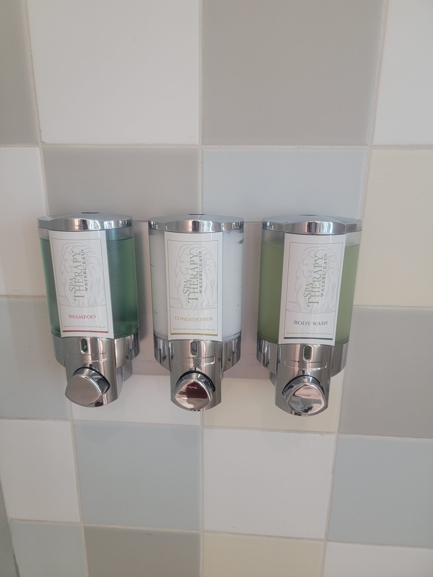 a group of soap dispensers on a tile wall