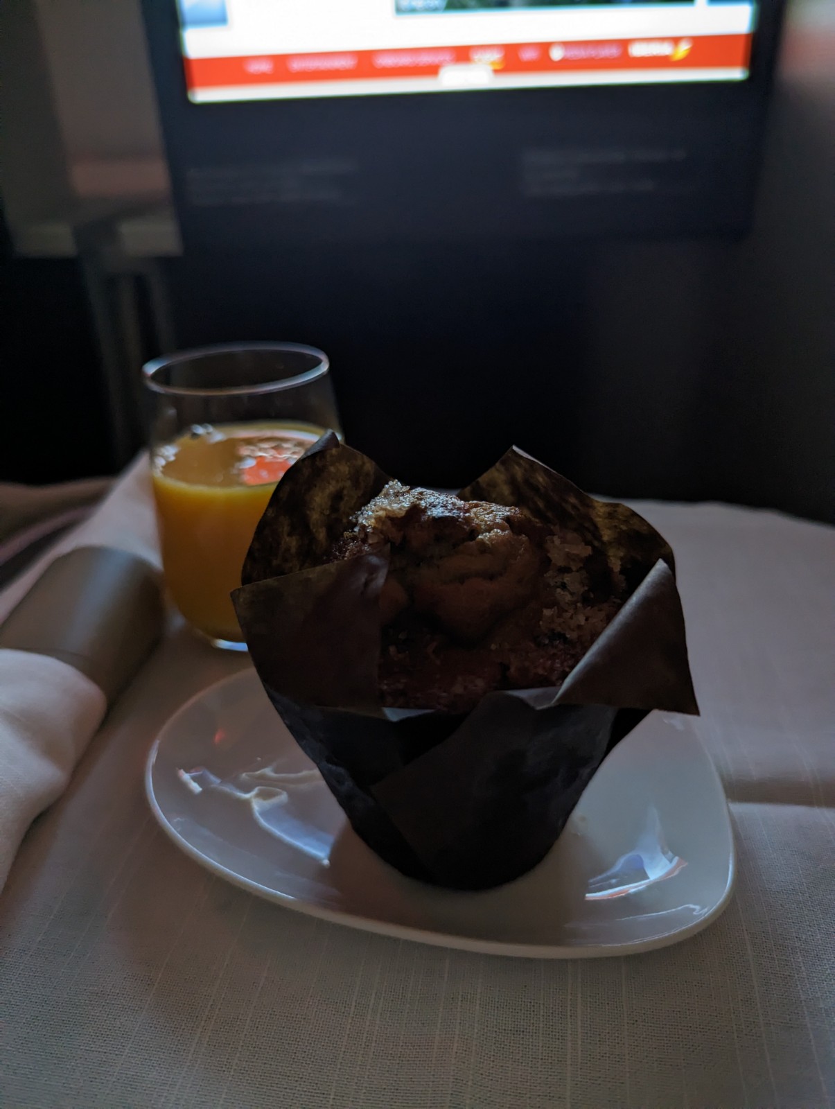 a muffin on a plate next to a glass of orange juice