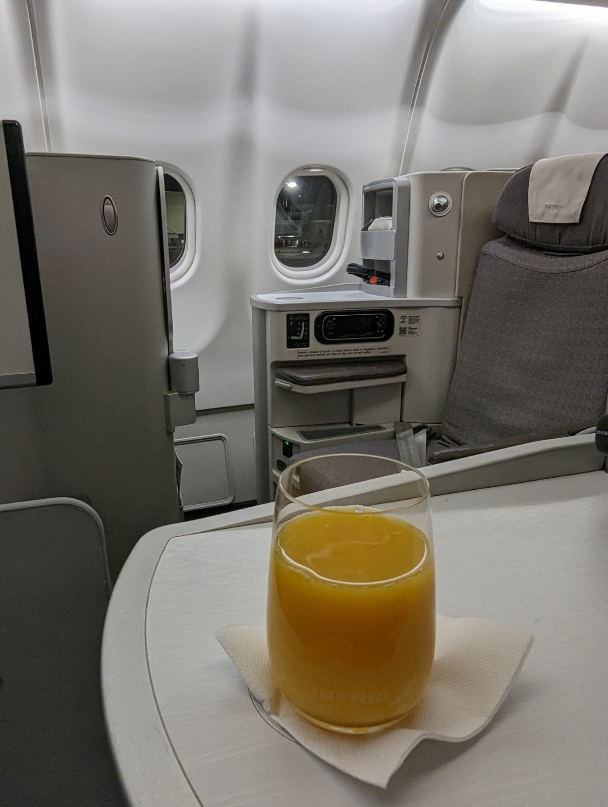 a glass of orange juice on a table in an airplane