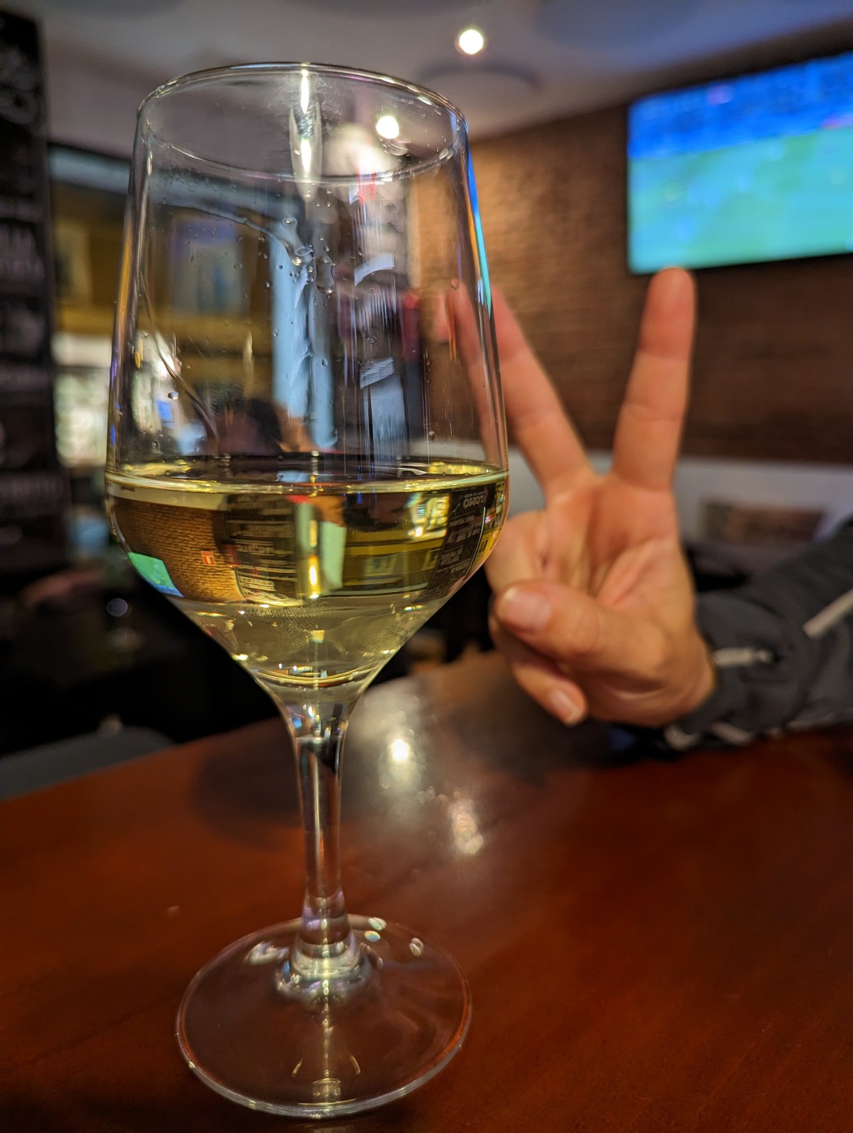 a glass of wine with a hand making a peace sign