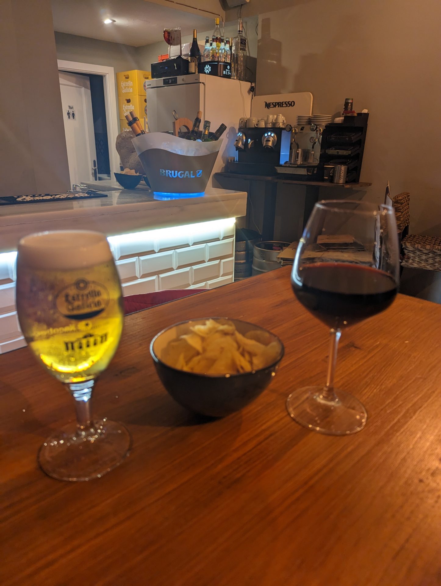 a glass of wine and a bowl of chips on a table