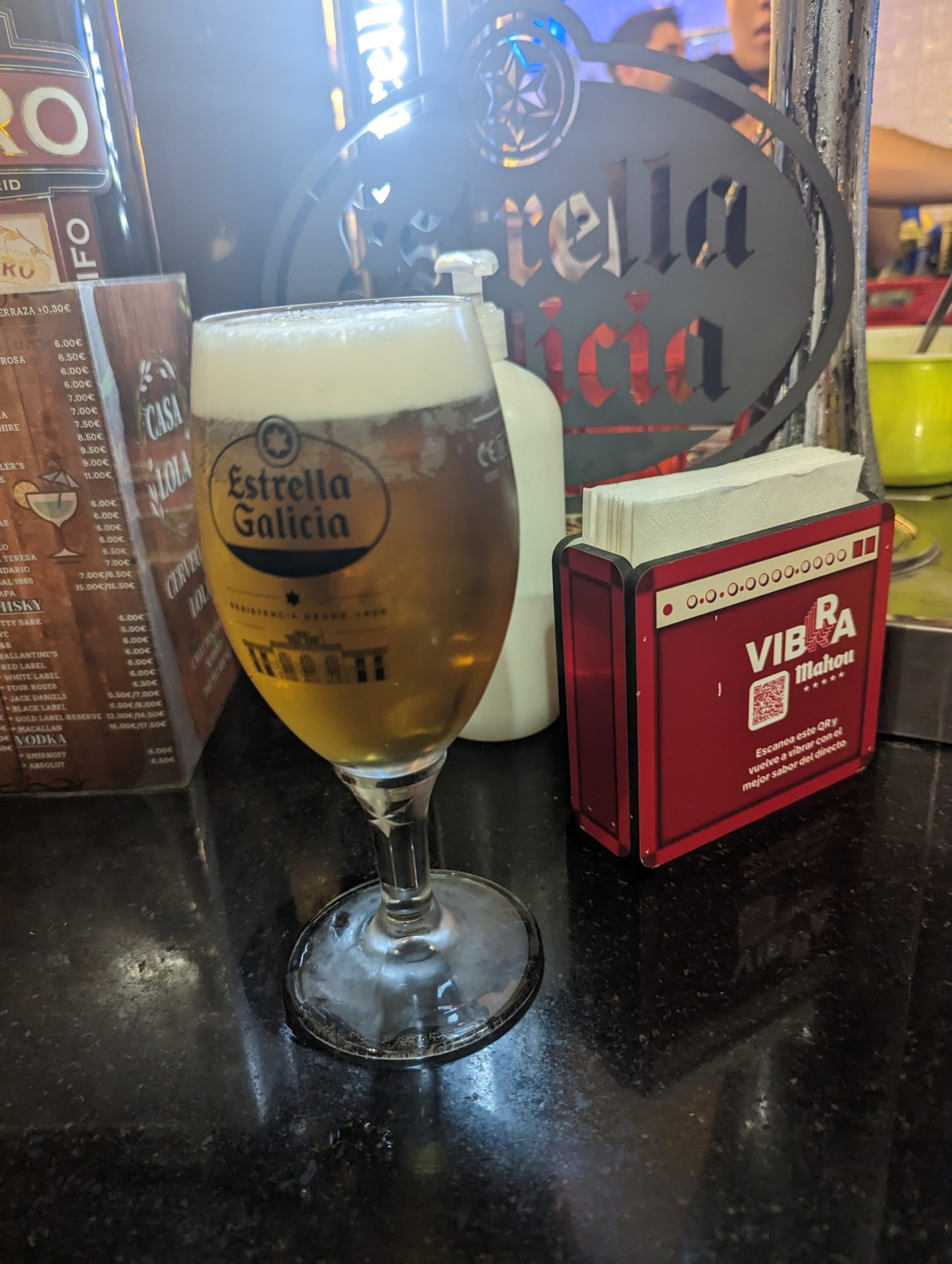 a glass of beer next to a box of napkins