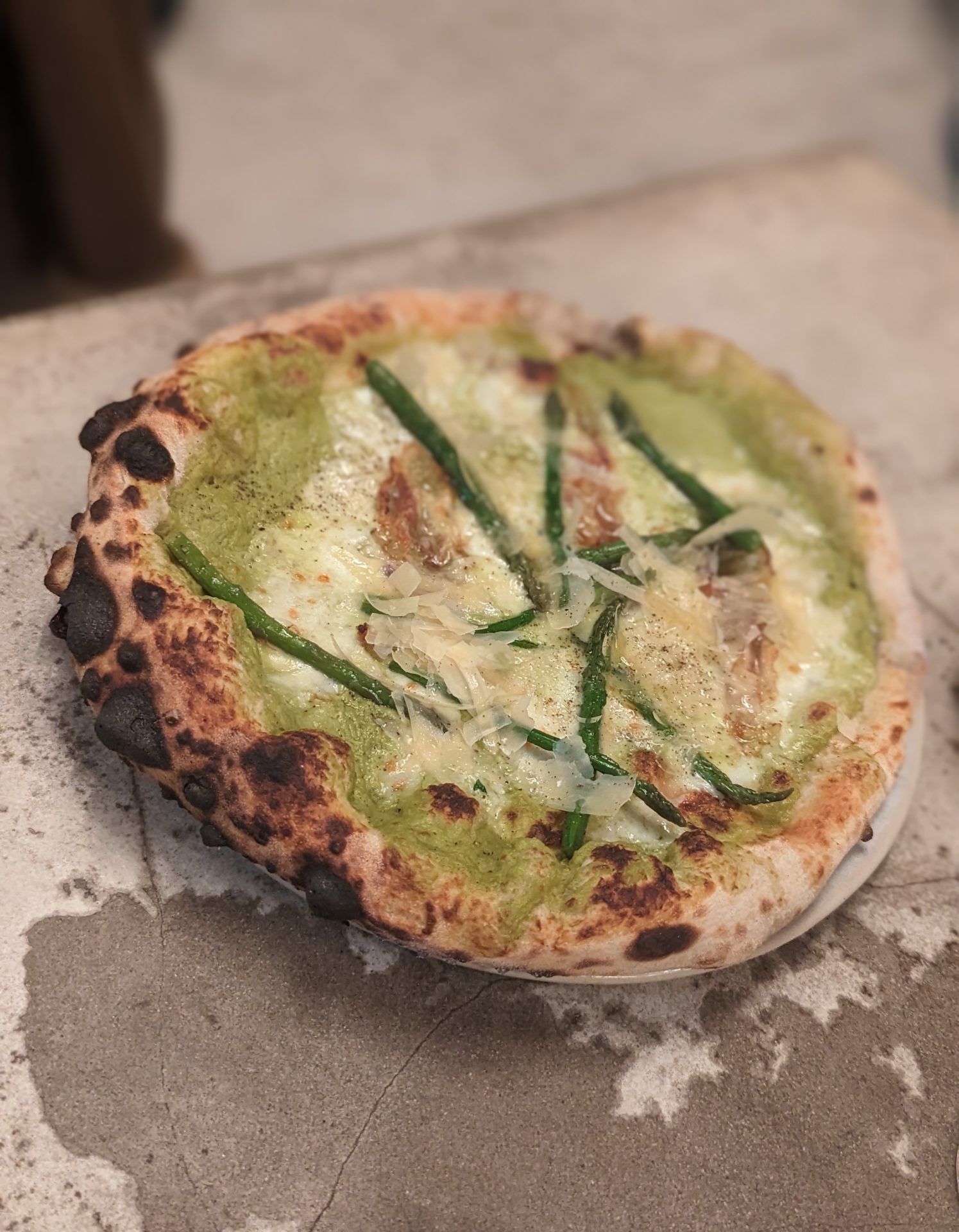 a pizza with green sauce and cheese