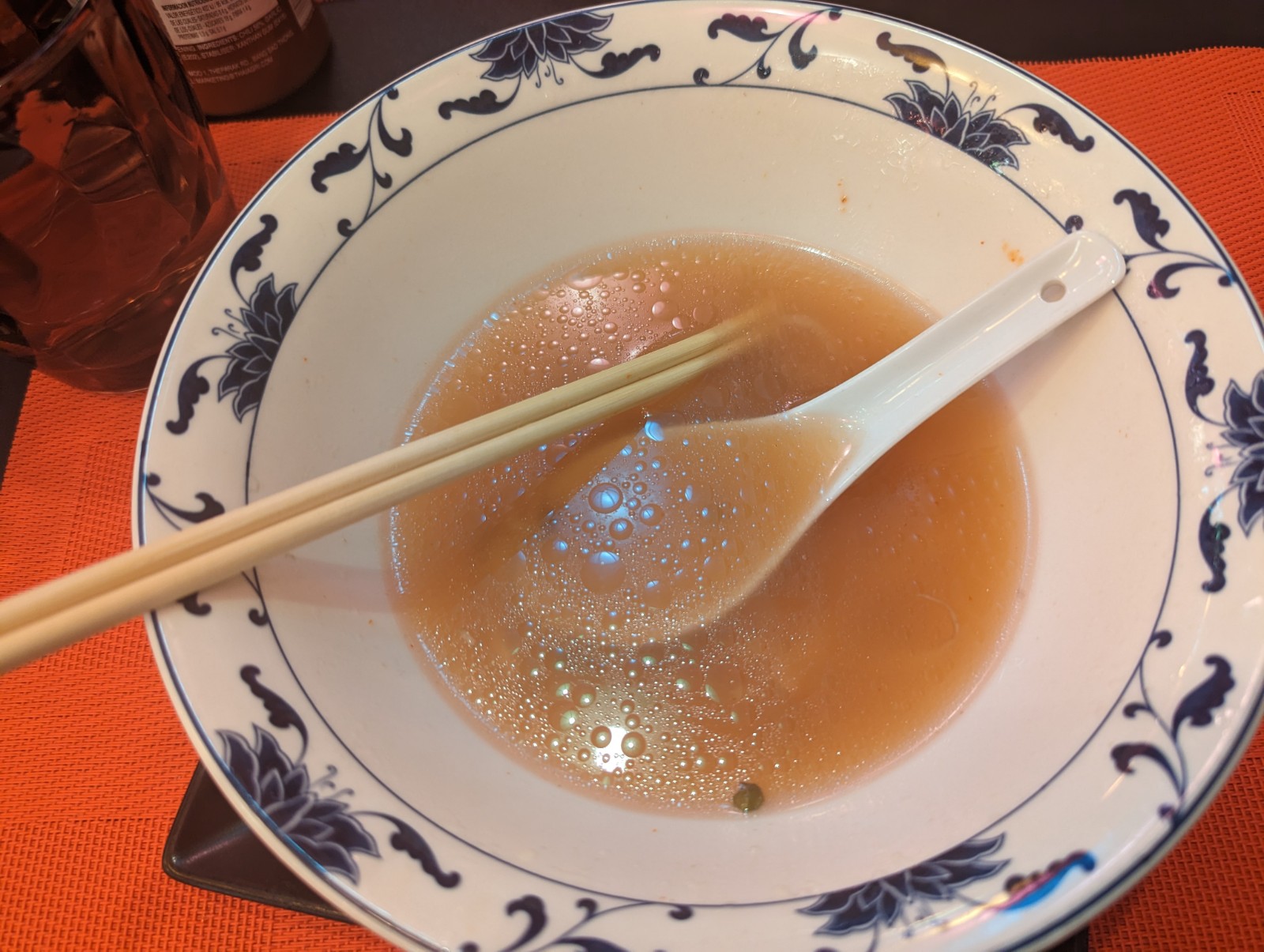 a bowl of soup with a spoon and chopsticks