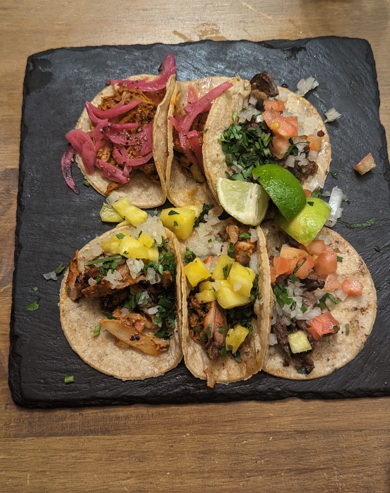 a group of tacos on a black plate