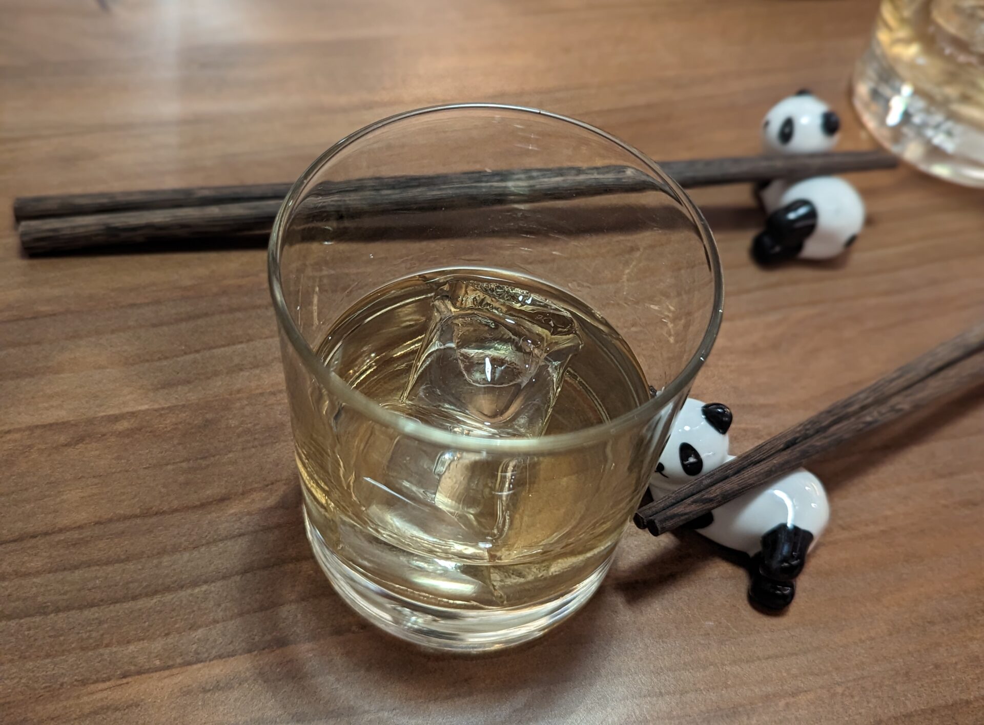 a glass of liquid and chopsticks on a table
