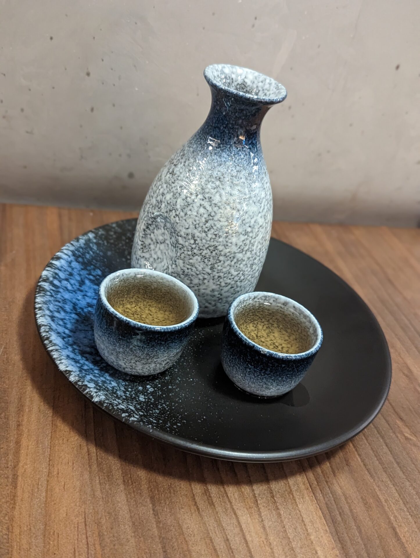 a ceramic bottle and cups on a plate