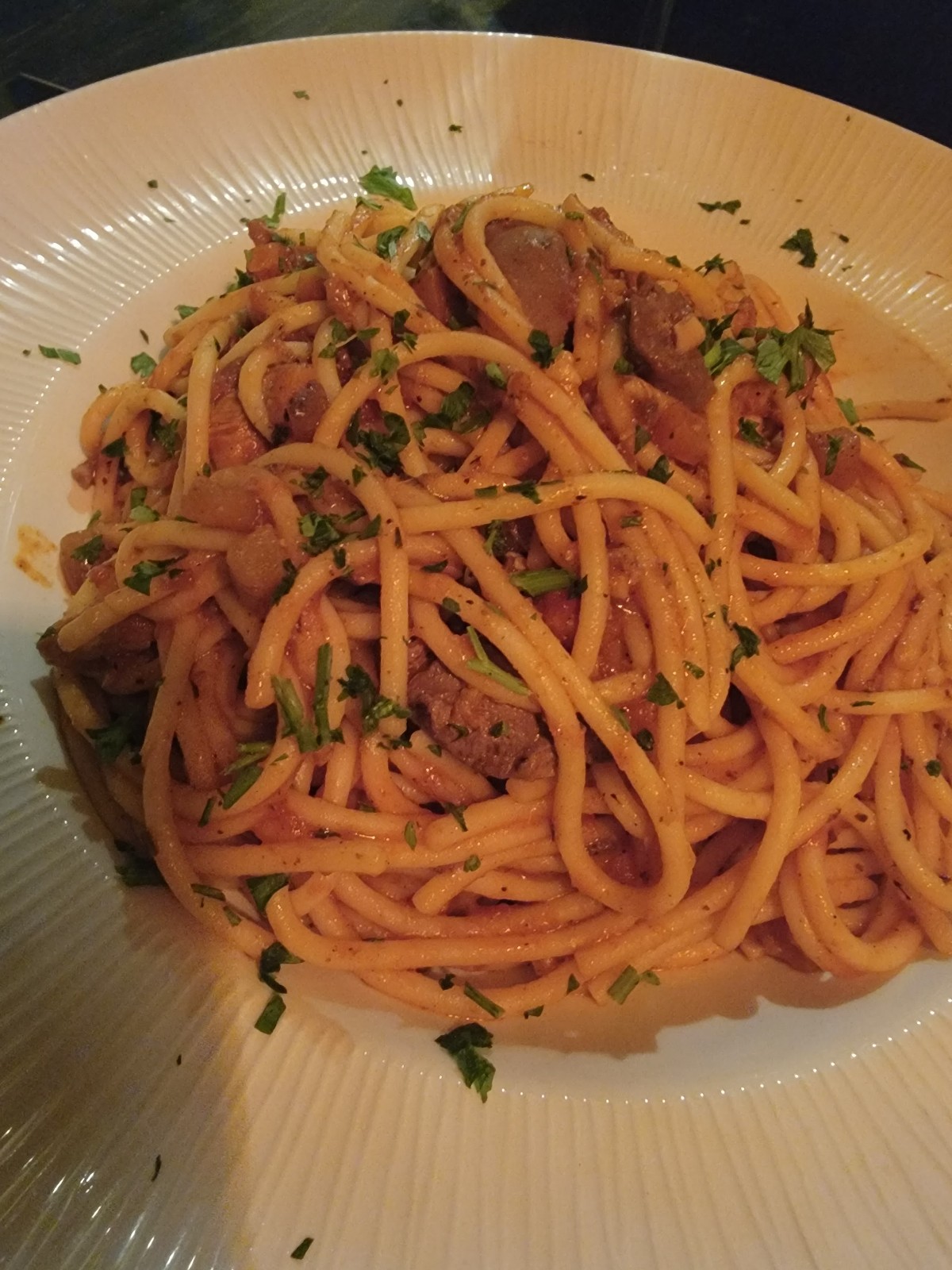 a plate of spaghetti with meat and parsley