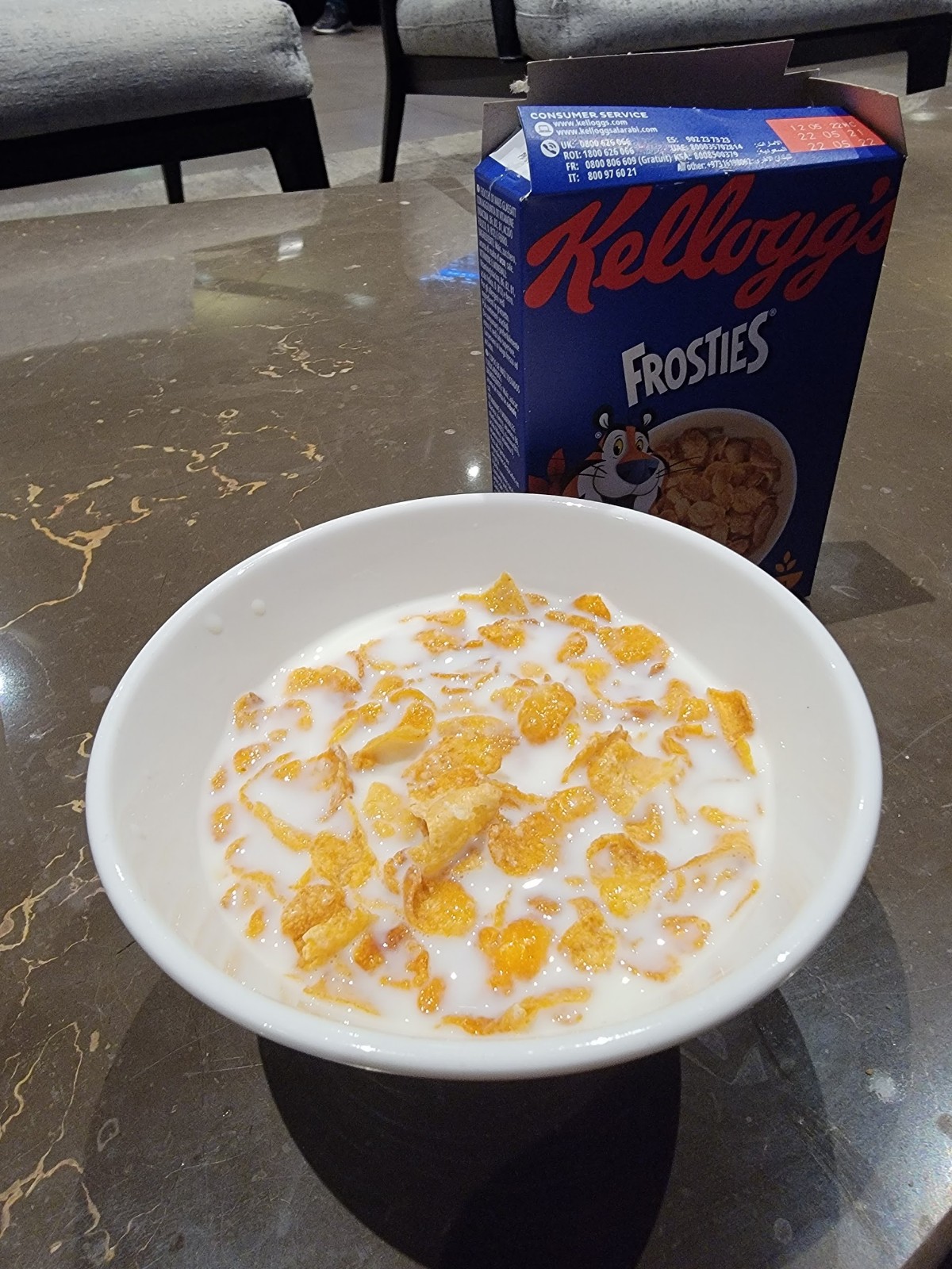 a bowl of cereal with milk and a box of cereal