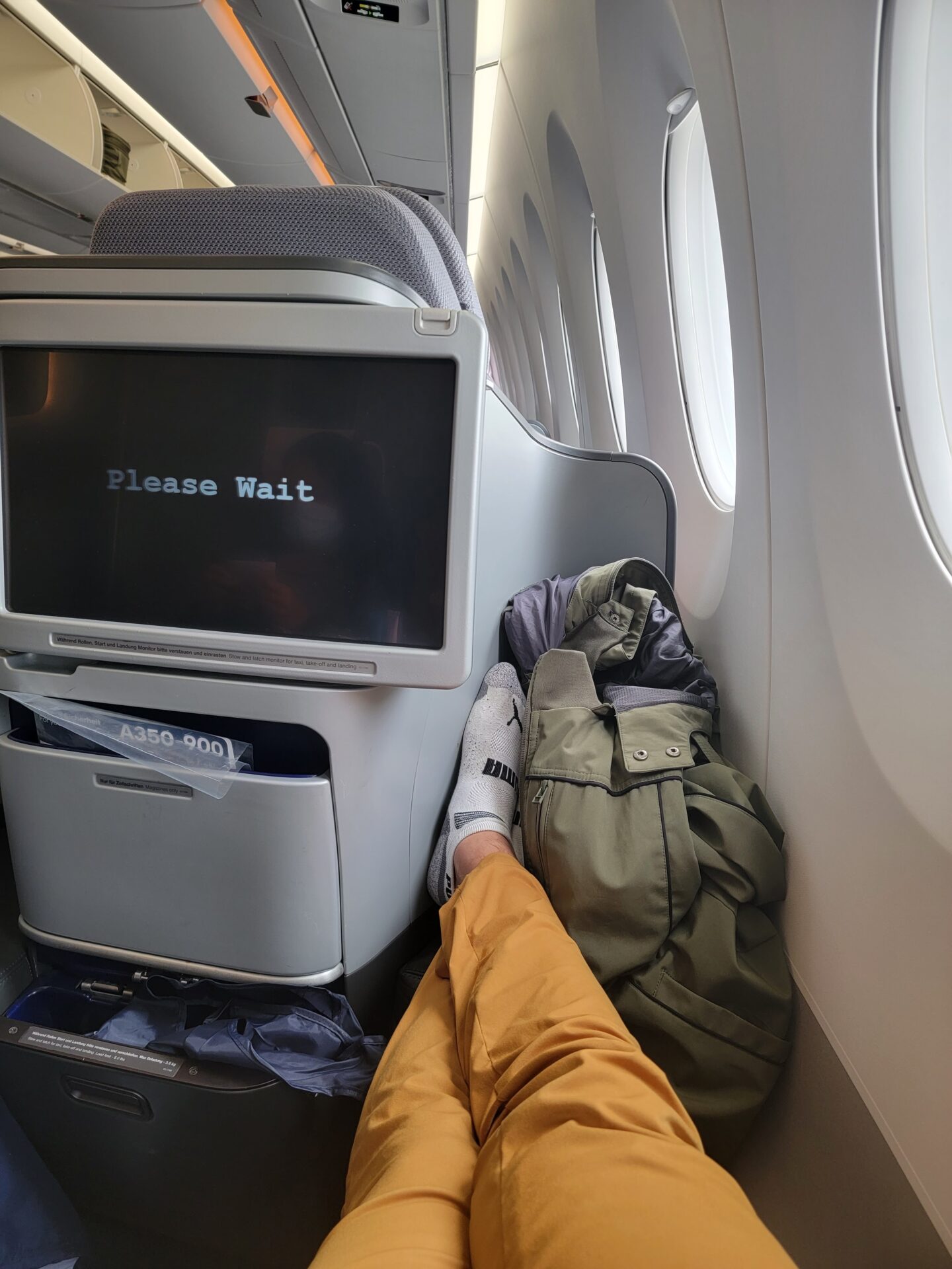 a person's feet on an airplane with a tv