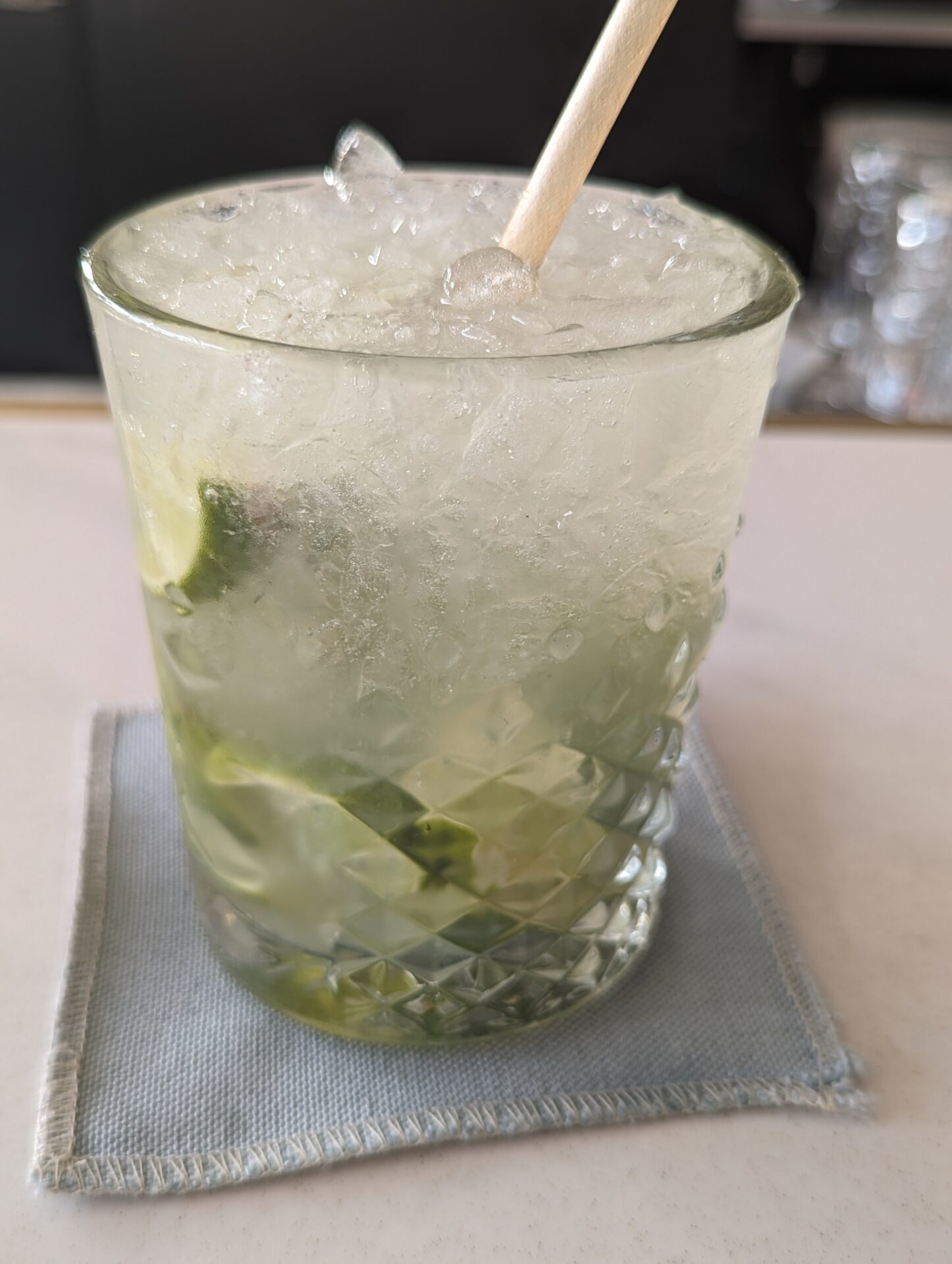 a glass with ice and lime on a napkin