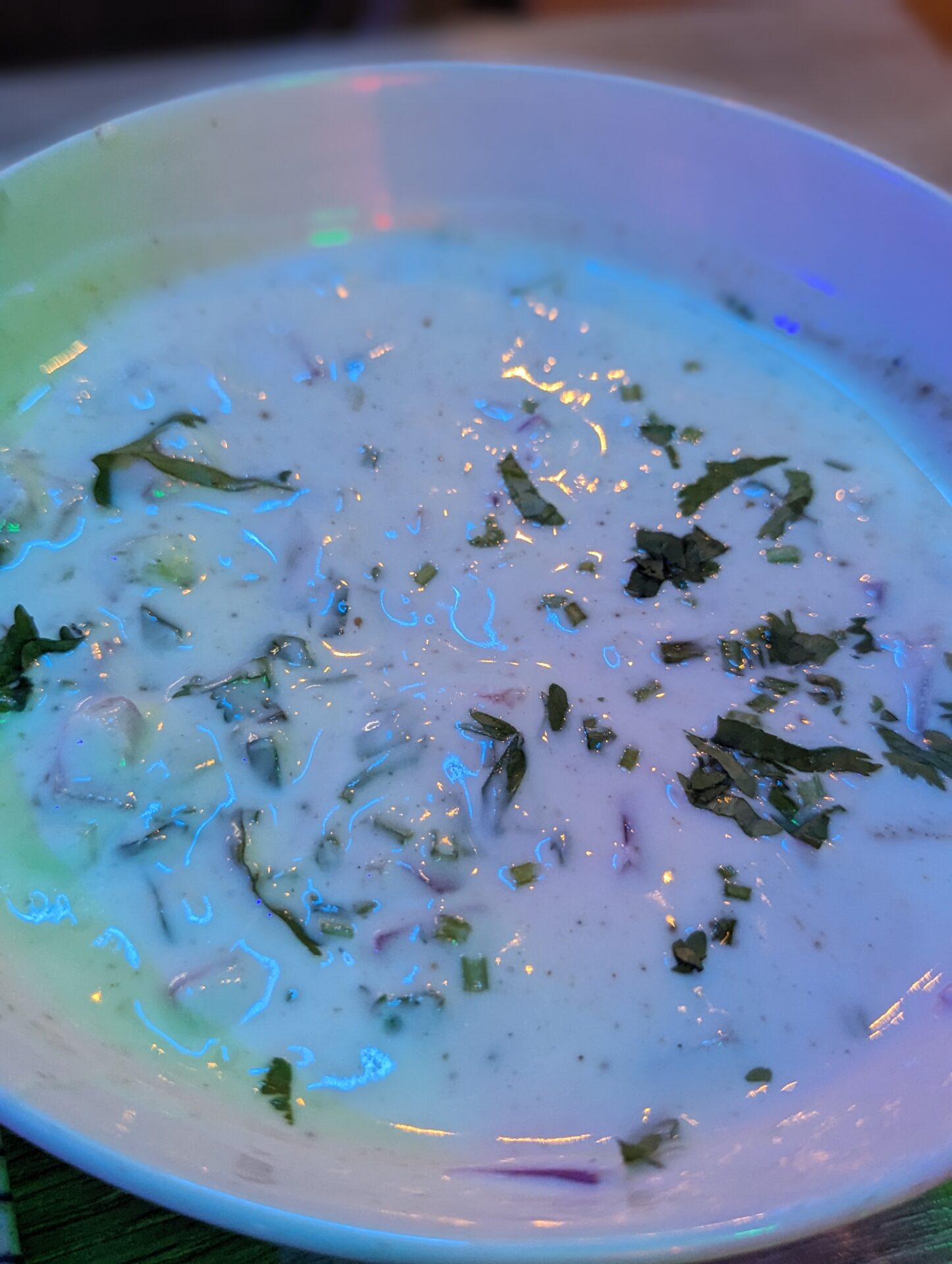 a bowl of soup with white liquid and green leaves