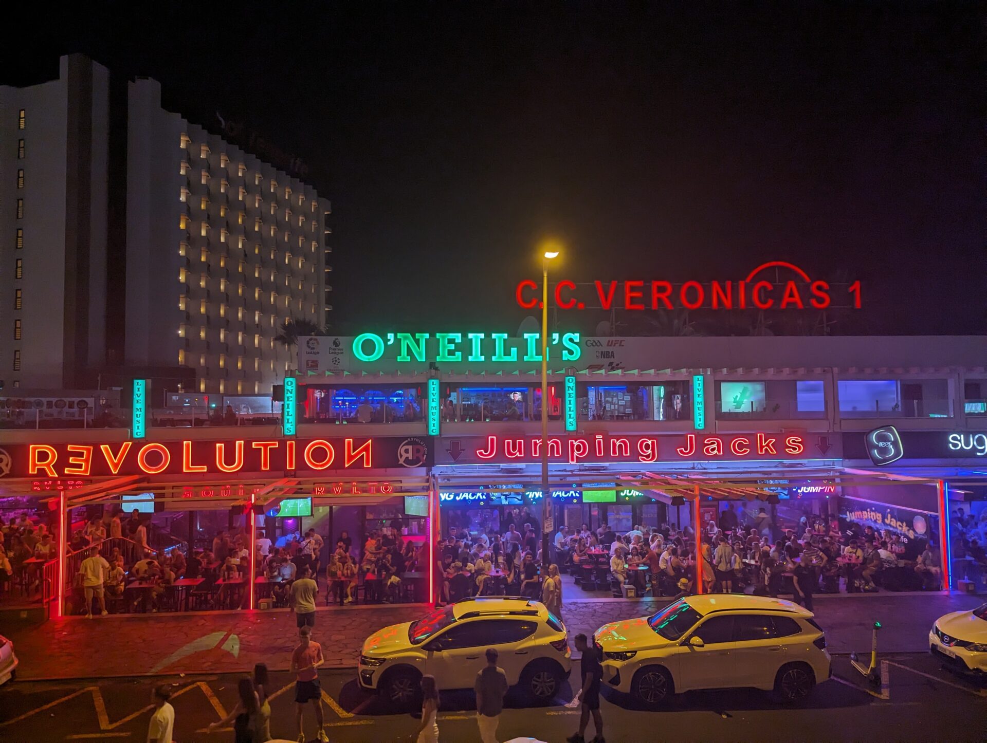 a group of people outside of a building with neon signs