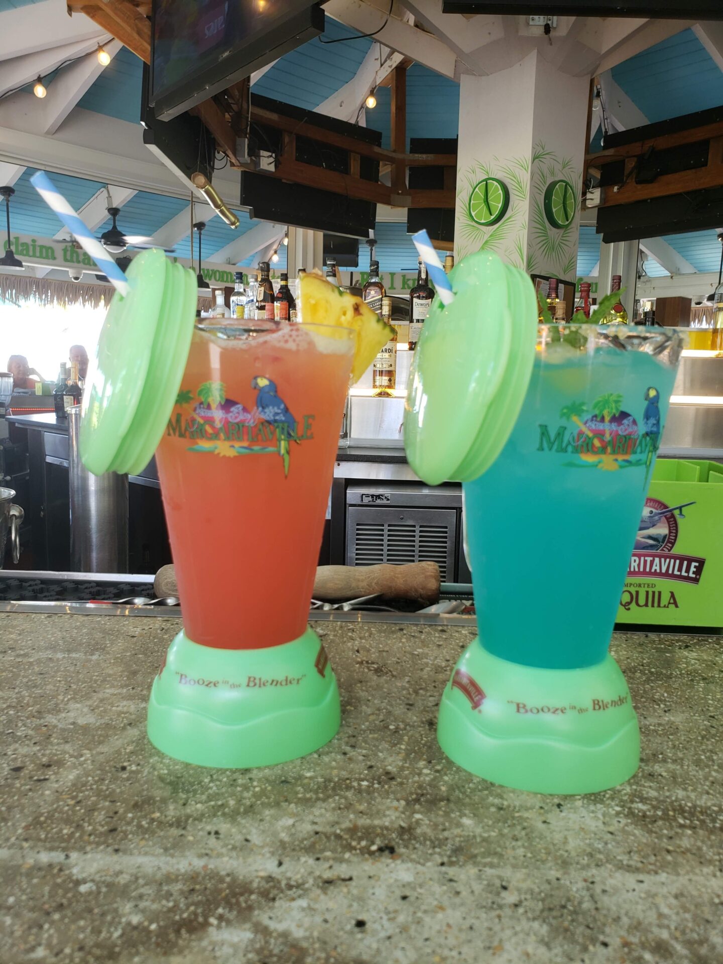 two glasses with colorful drinks on a counter