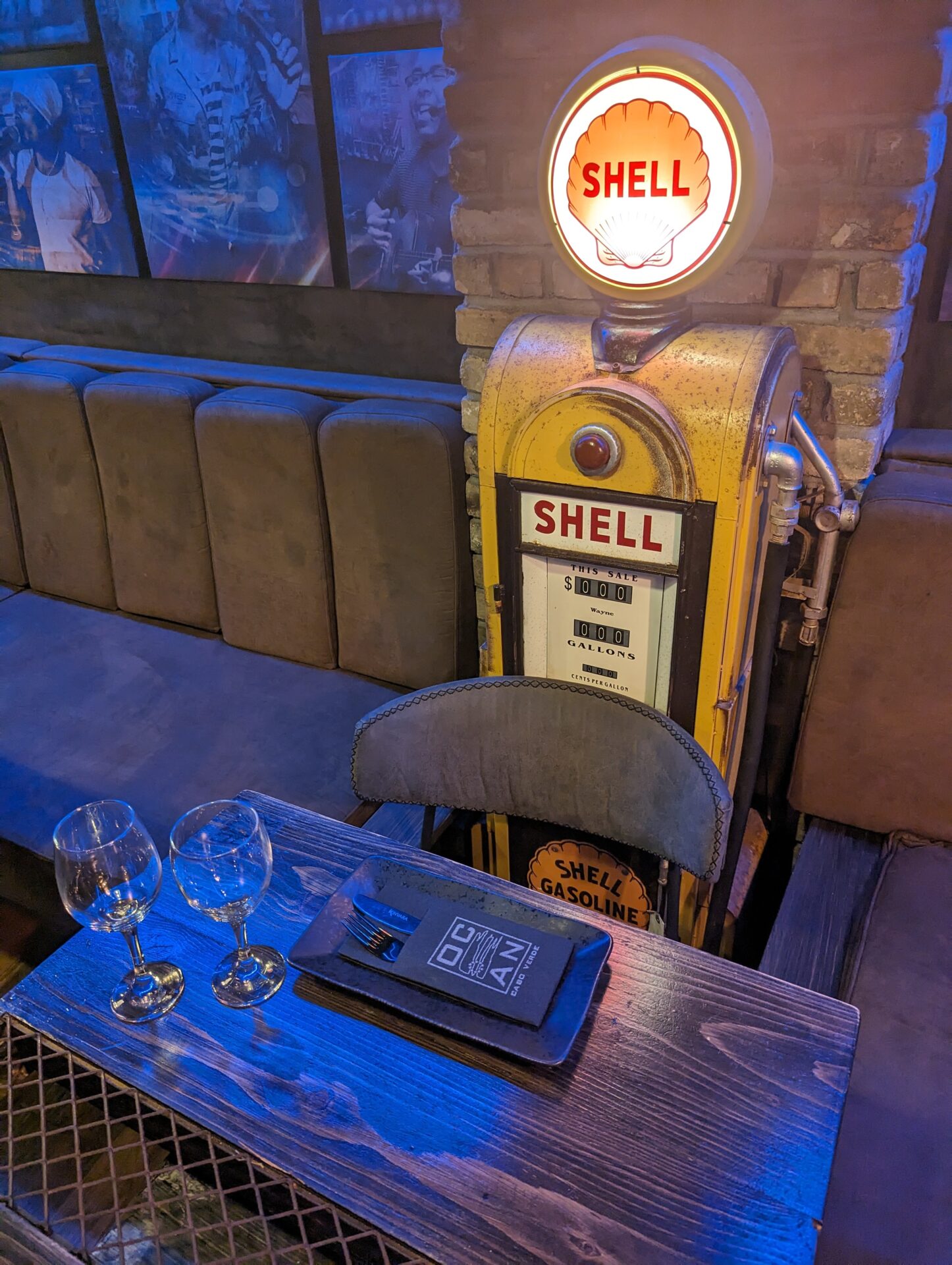 a gas pump with a lit up sign on top of a table with wine glasses