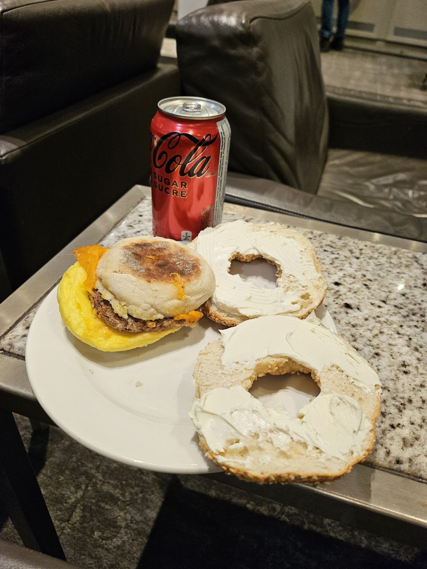 a bagel sandwich and a soda can on a table