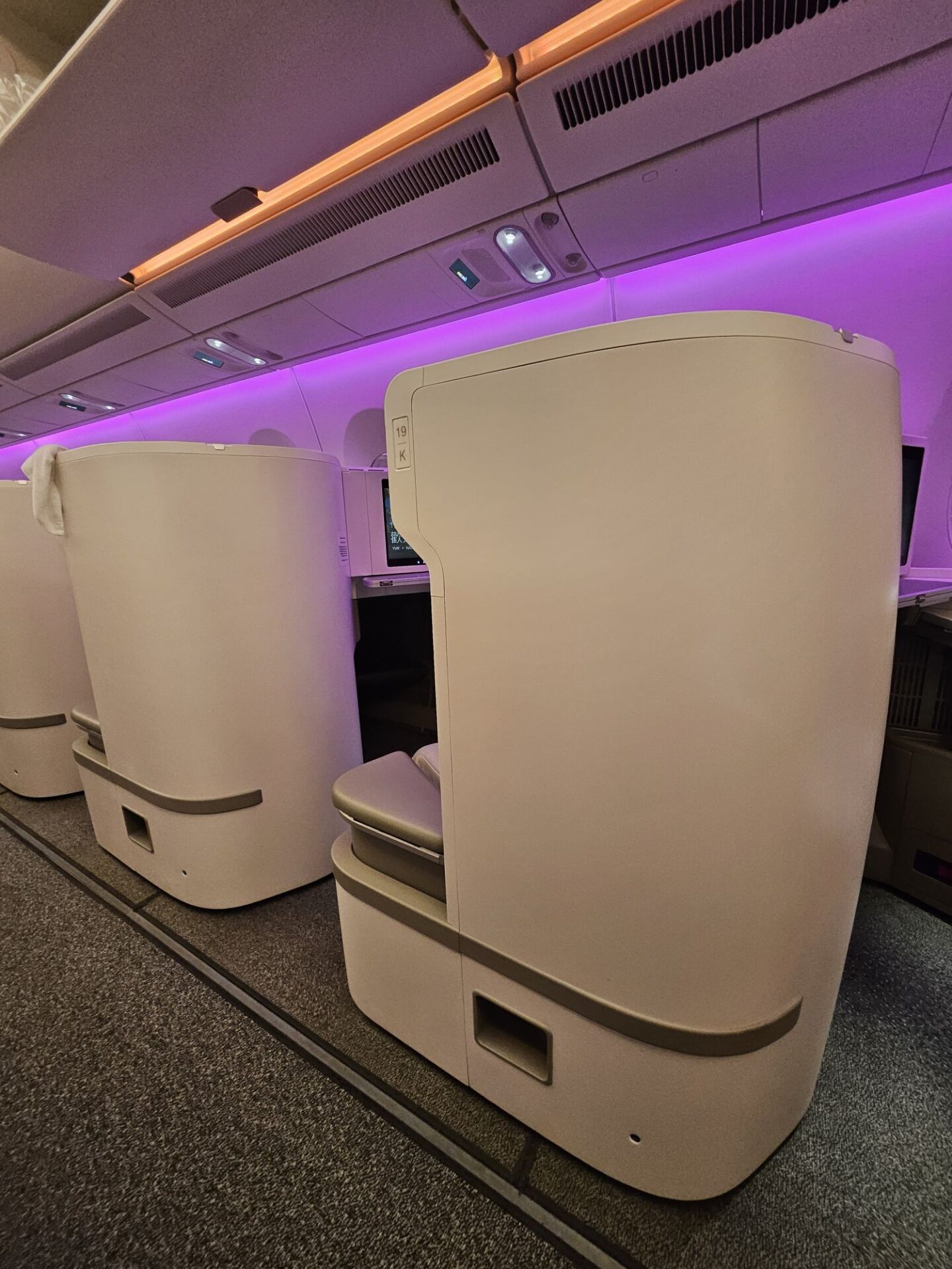 a row of white chairs in a room with purple lighting