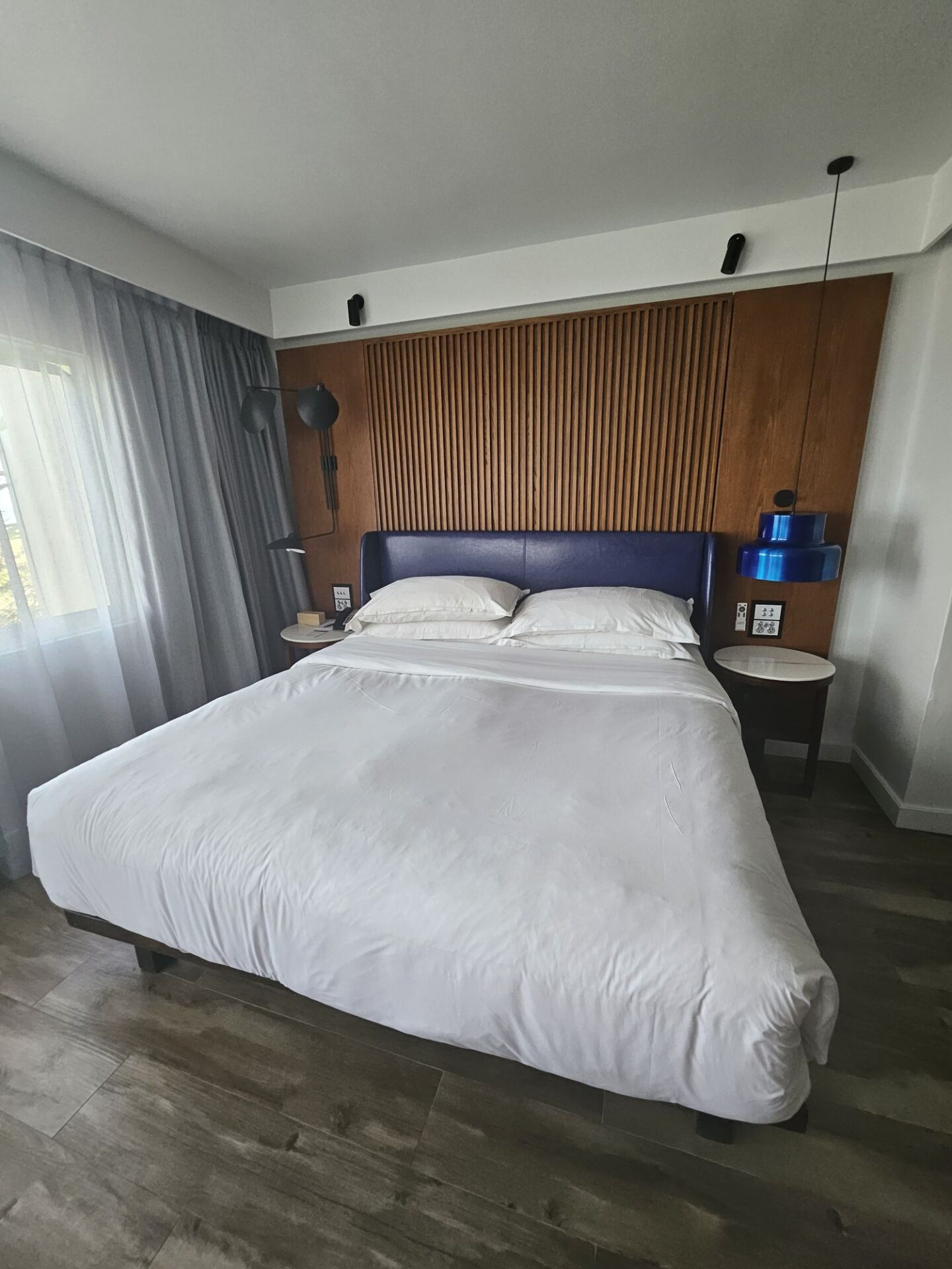 a bed with white sheets and blue headboard in a room