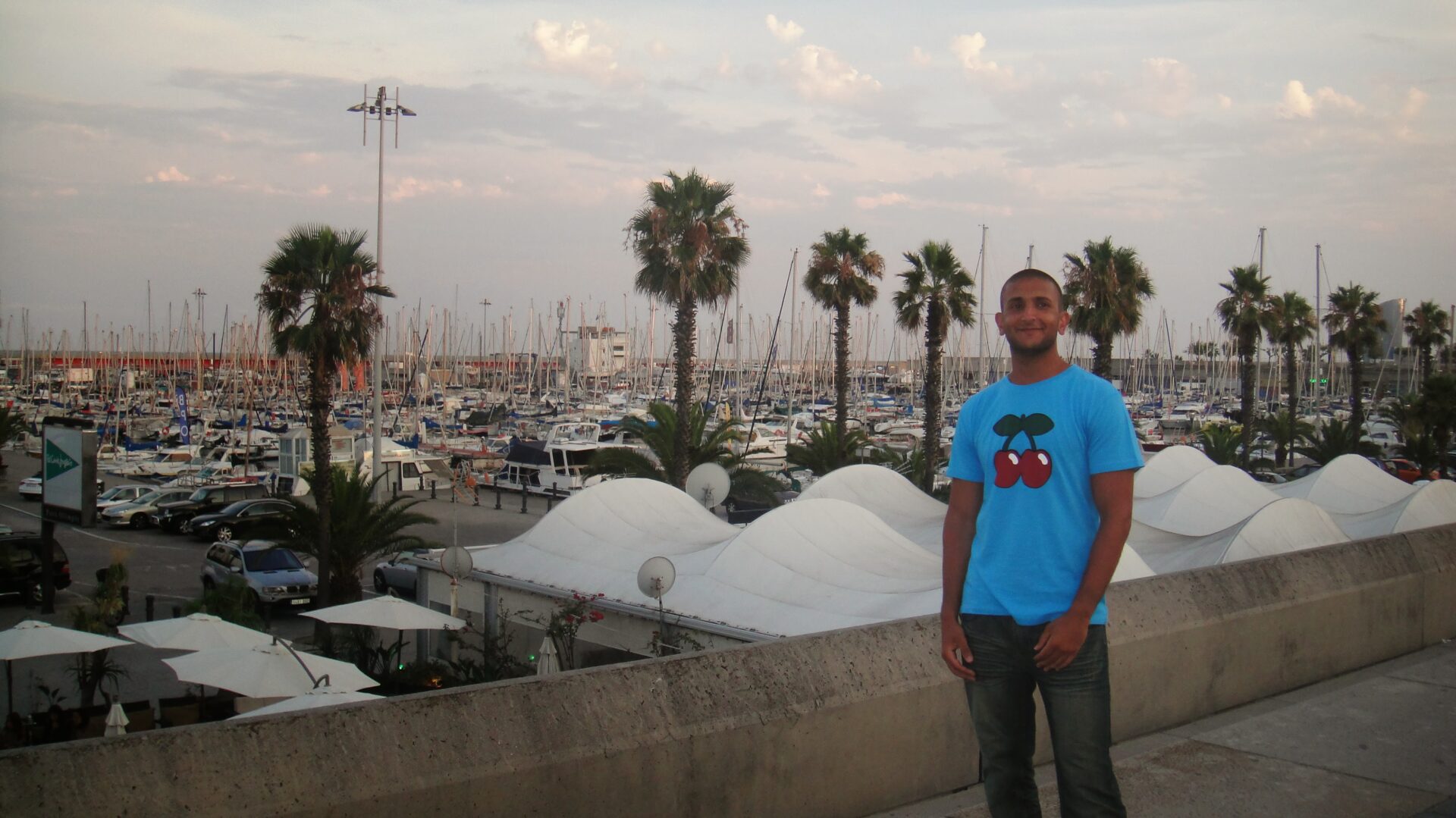 a man standing on a ledge with a marina and boats in the background