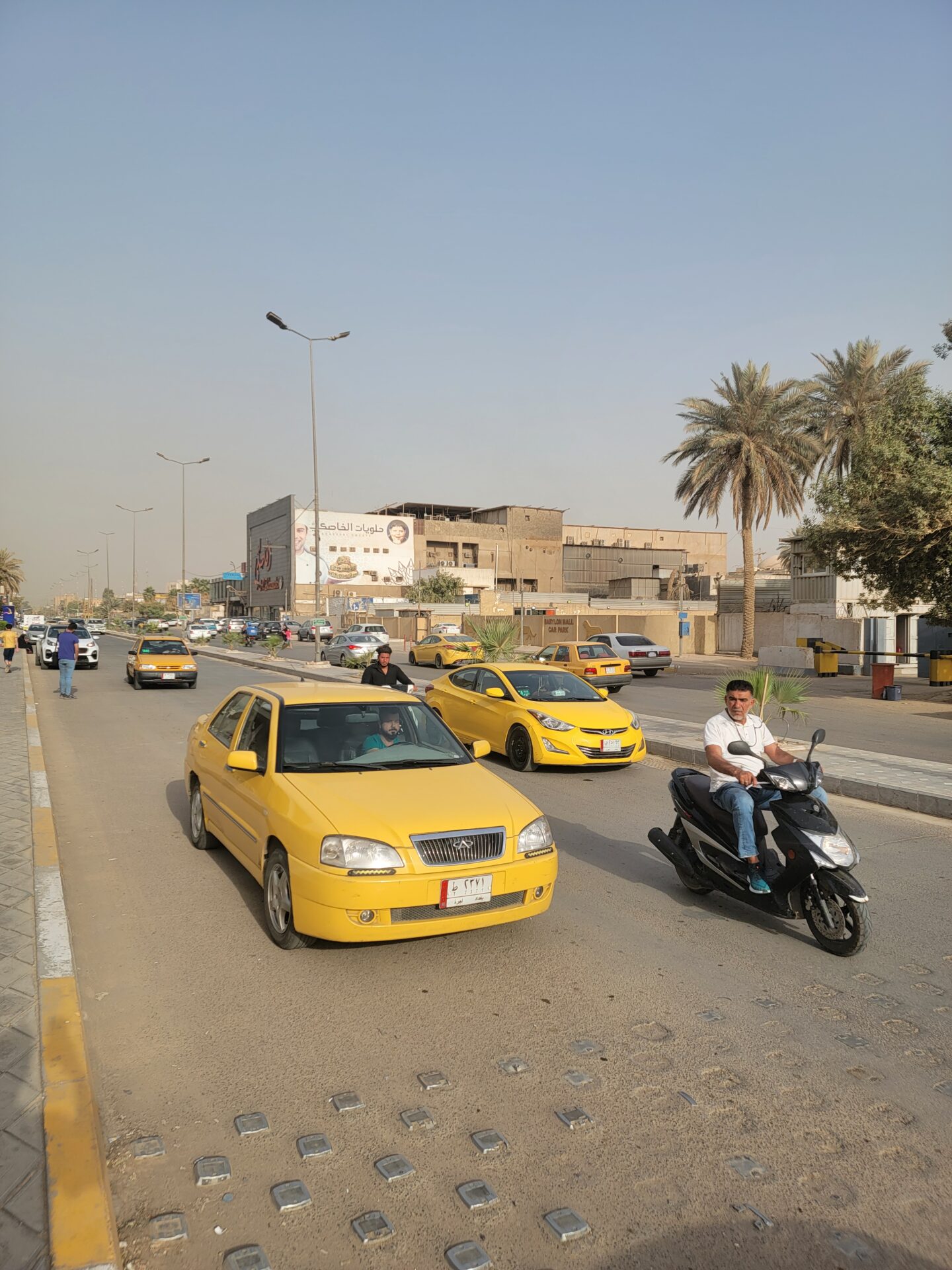 a man riding a scooter on a road with cars and buildings