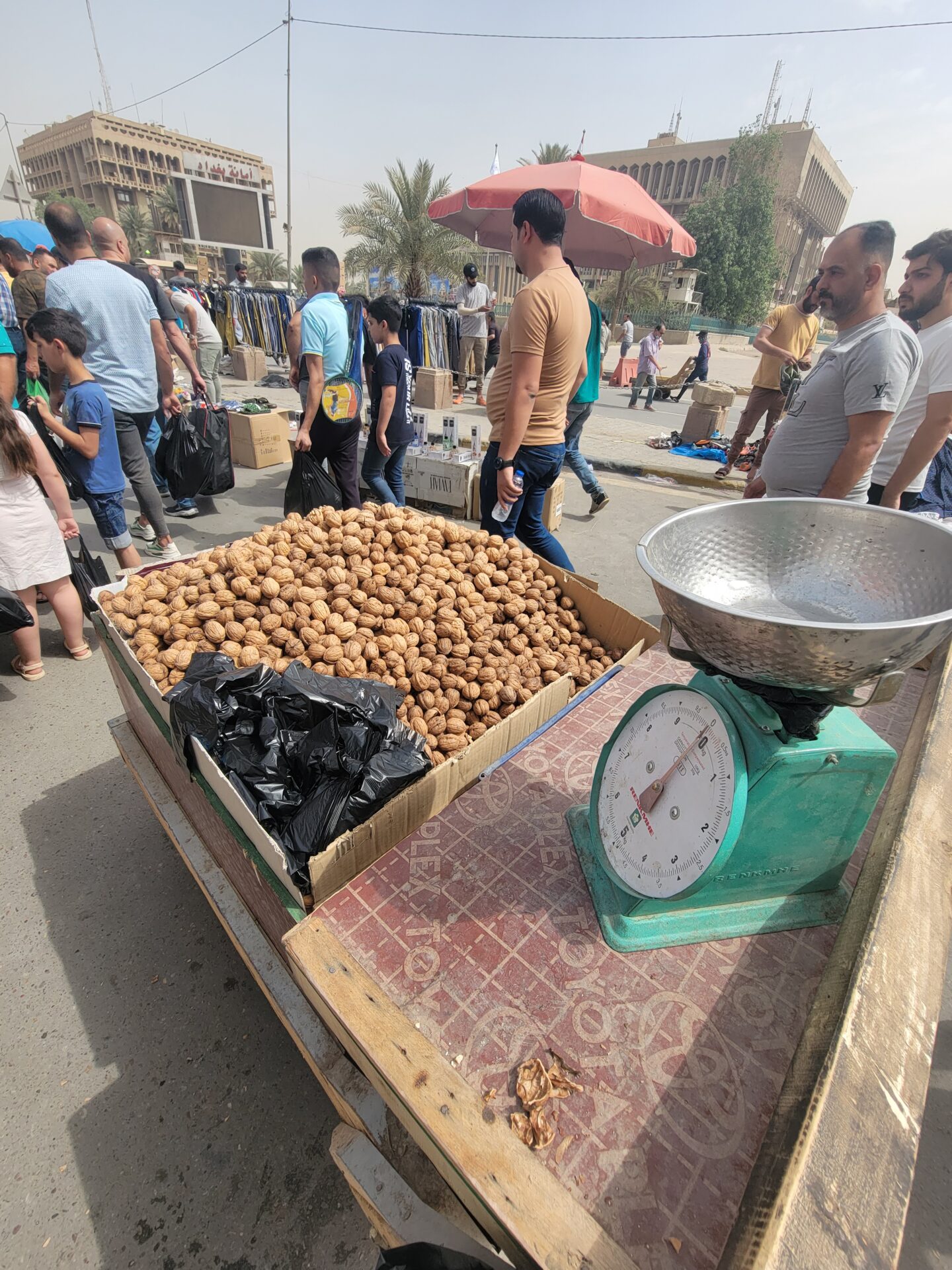 a group of people standing around a table with a pile of potatoes
