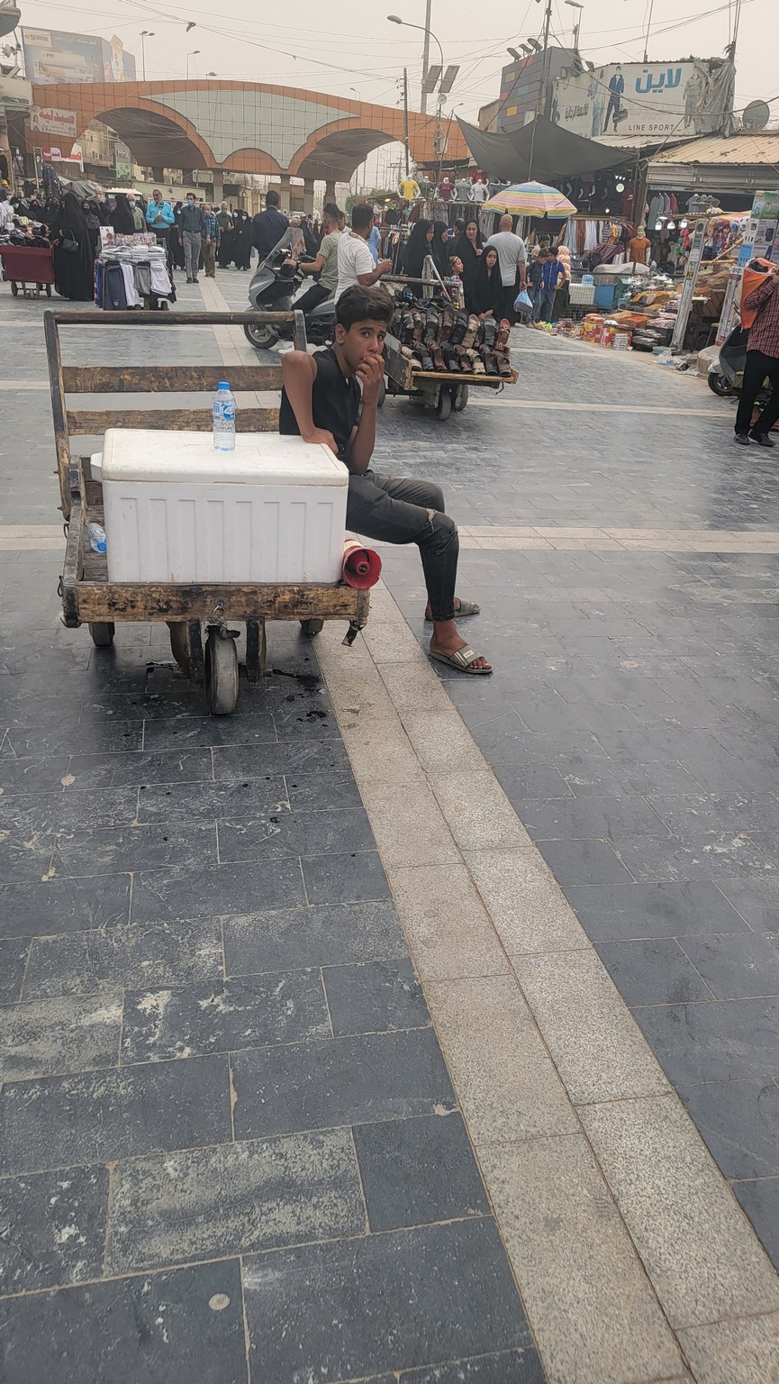 a man sitting on a cart with a cooler on it
