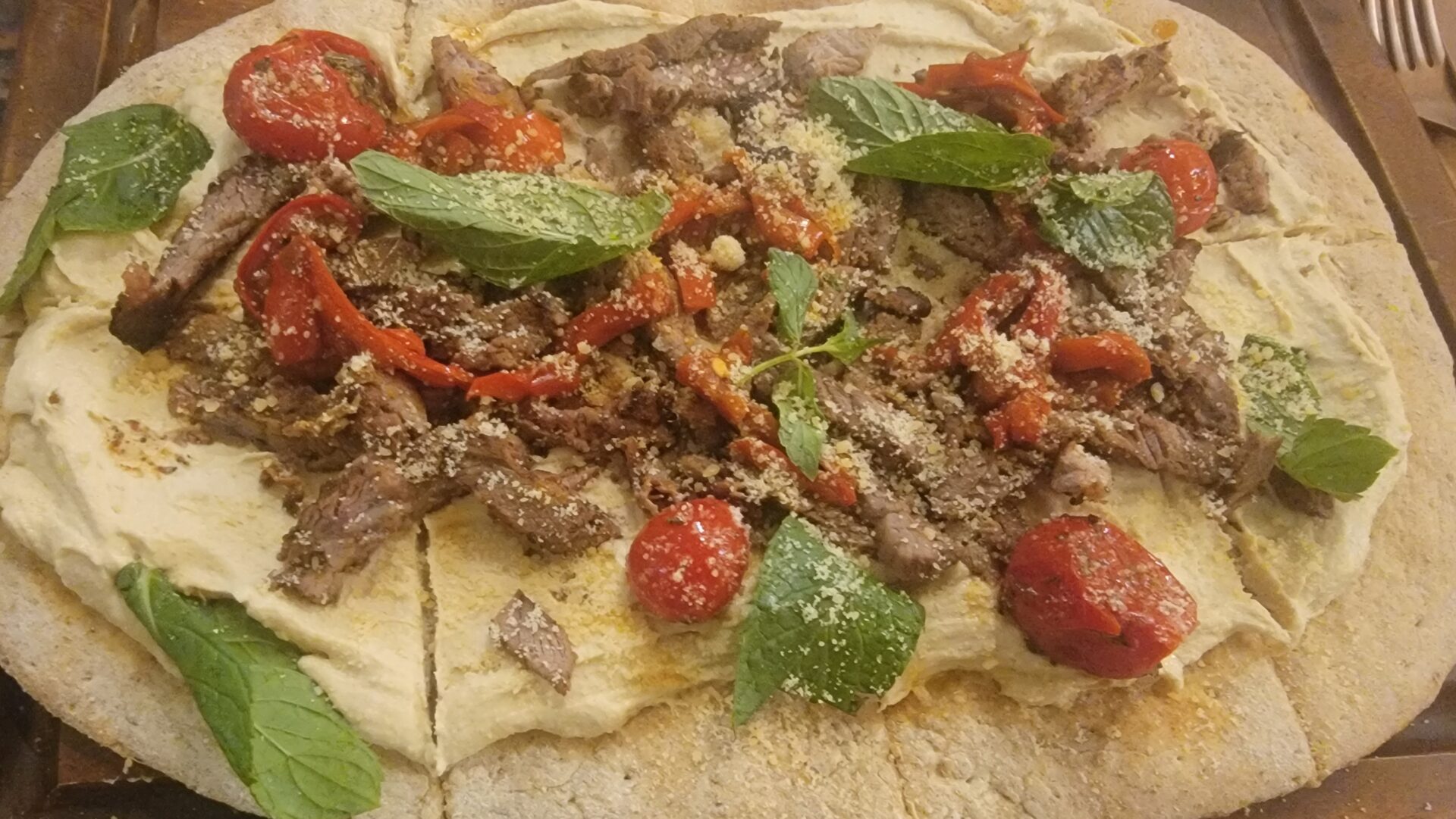 a pizza with meat and vegetables on a flatbread