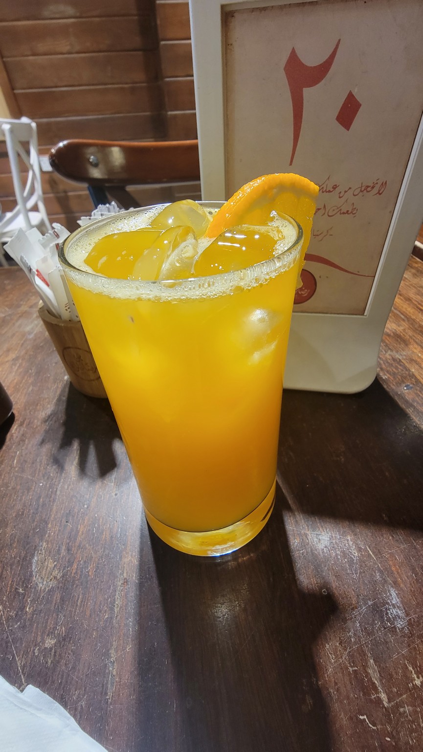 a glass of orange juice with ice and a slice of orange