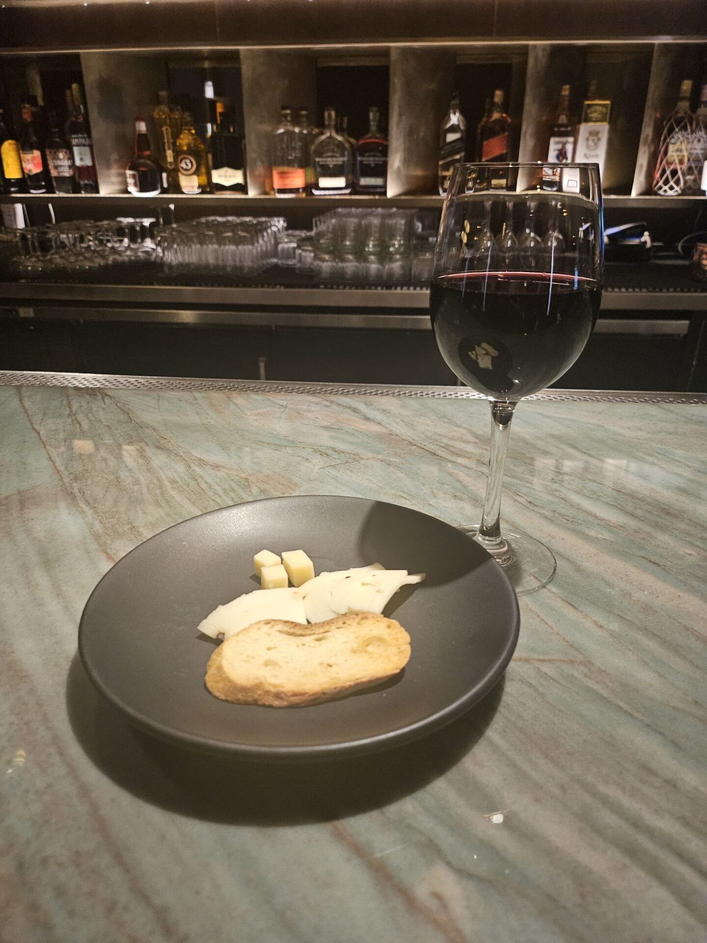 a plate of cheese and bread on a table with a glass of wine