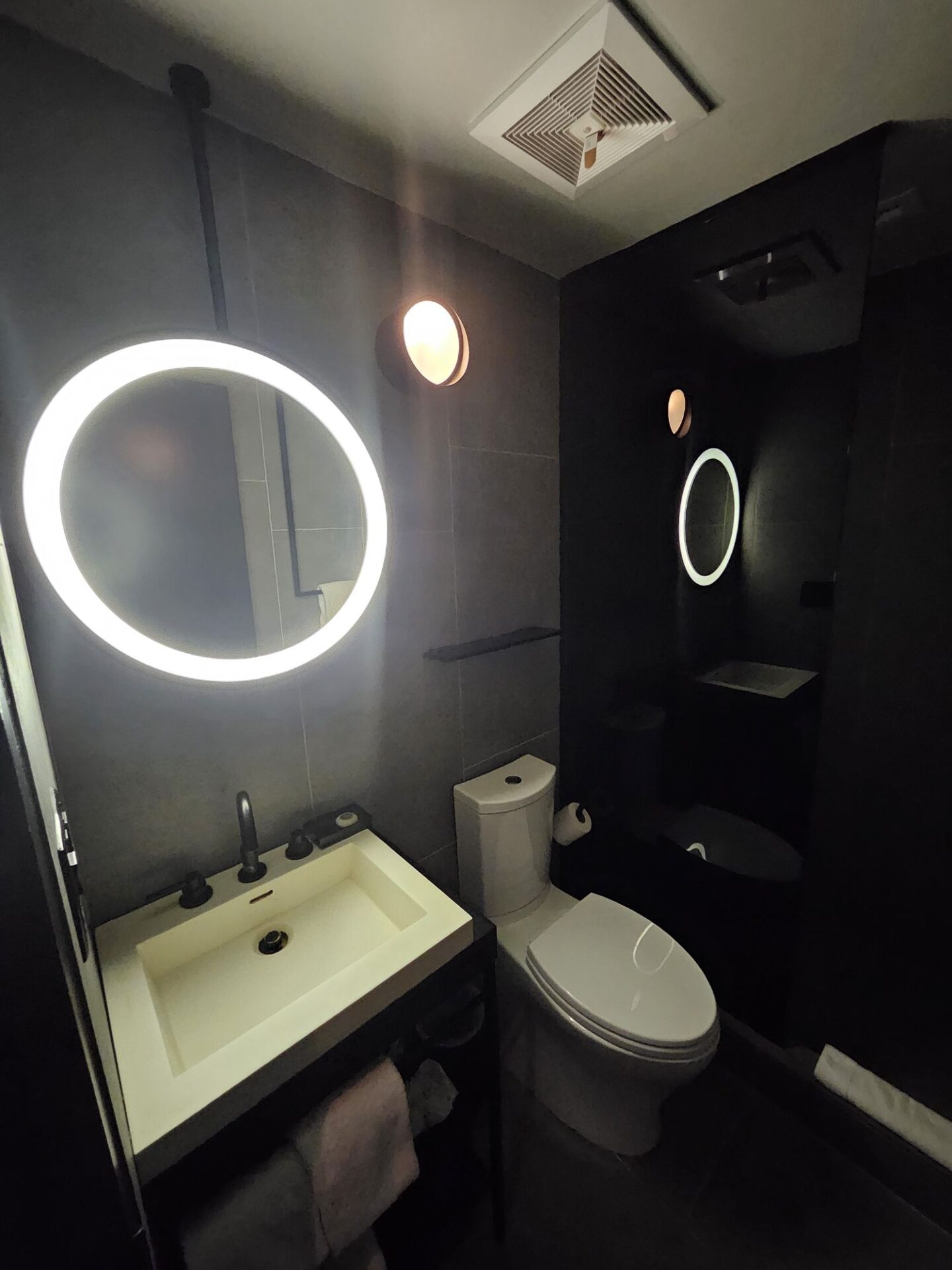 a bathroom with a round mirror and a toilet