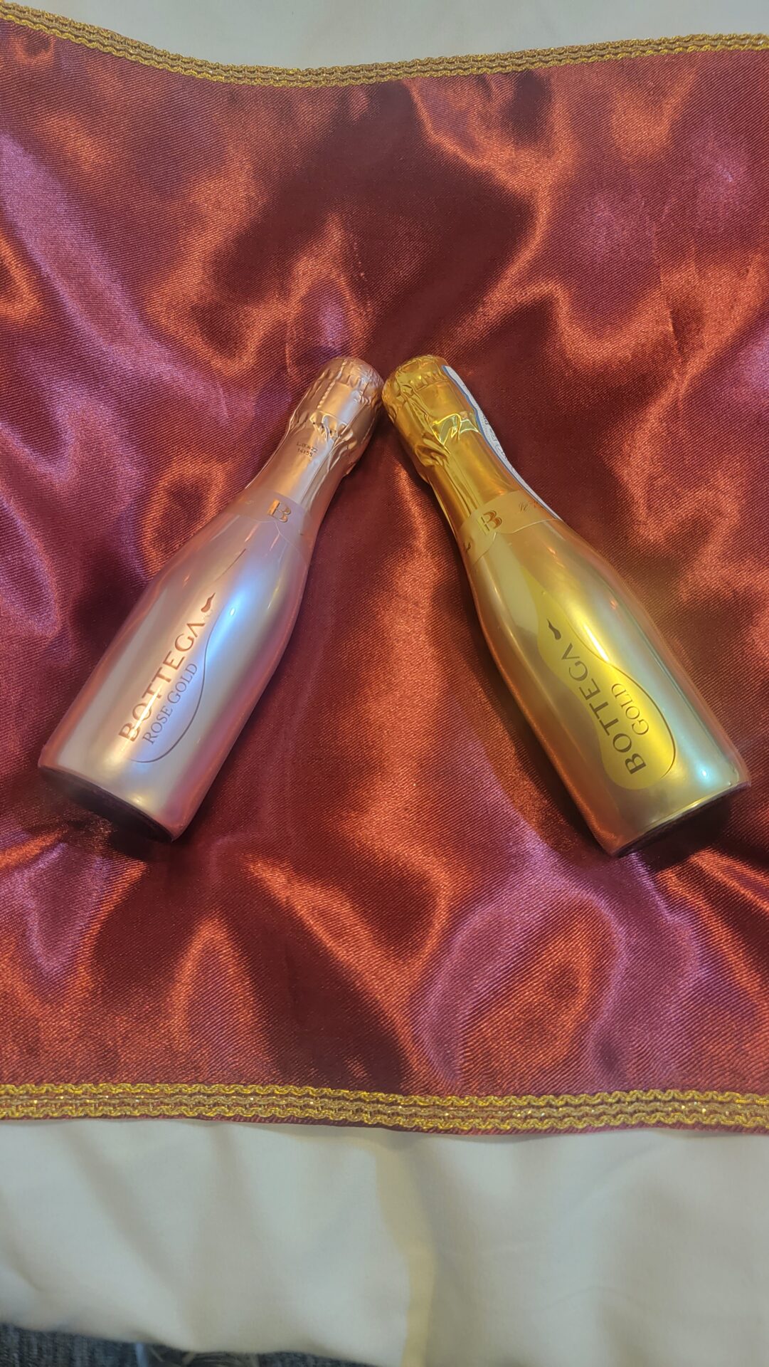 two champagne bottles on a red satin