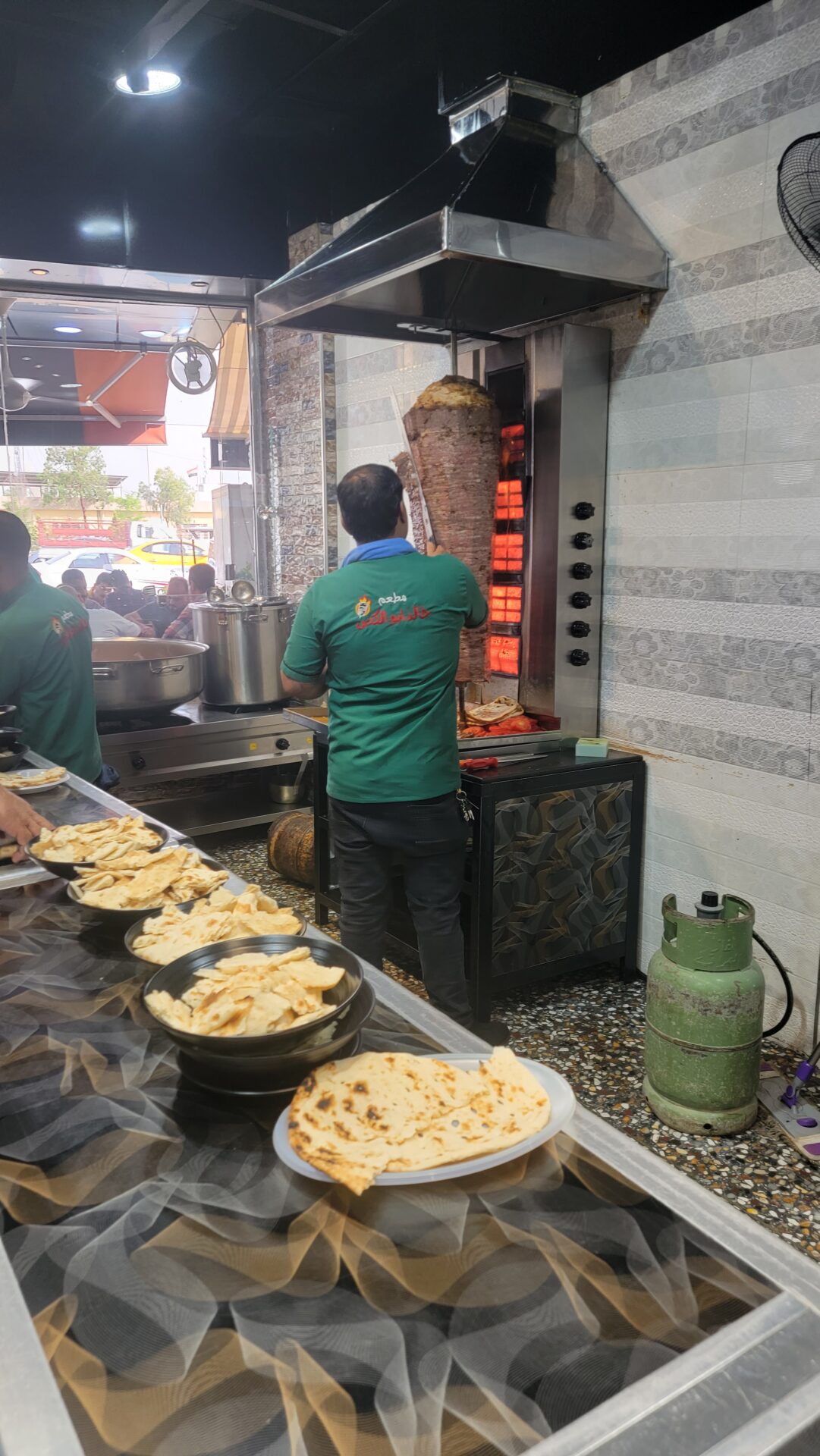 a man standing in a kitchen with a large meat grill