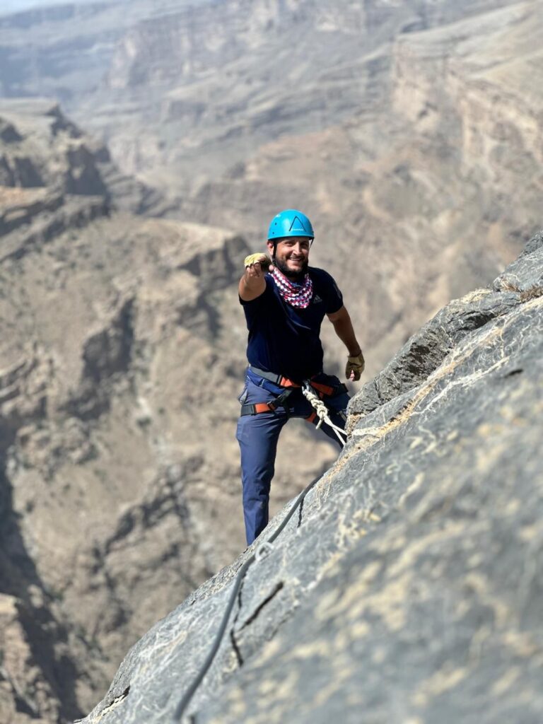 a man wearing a helmet and climbing a rock