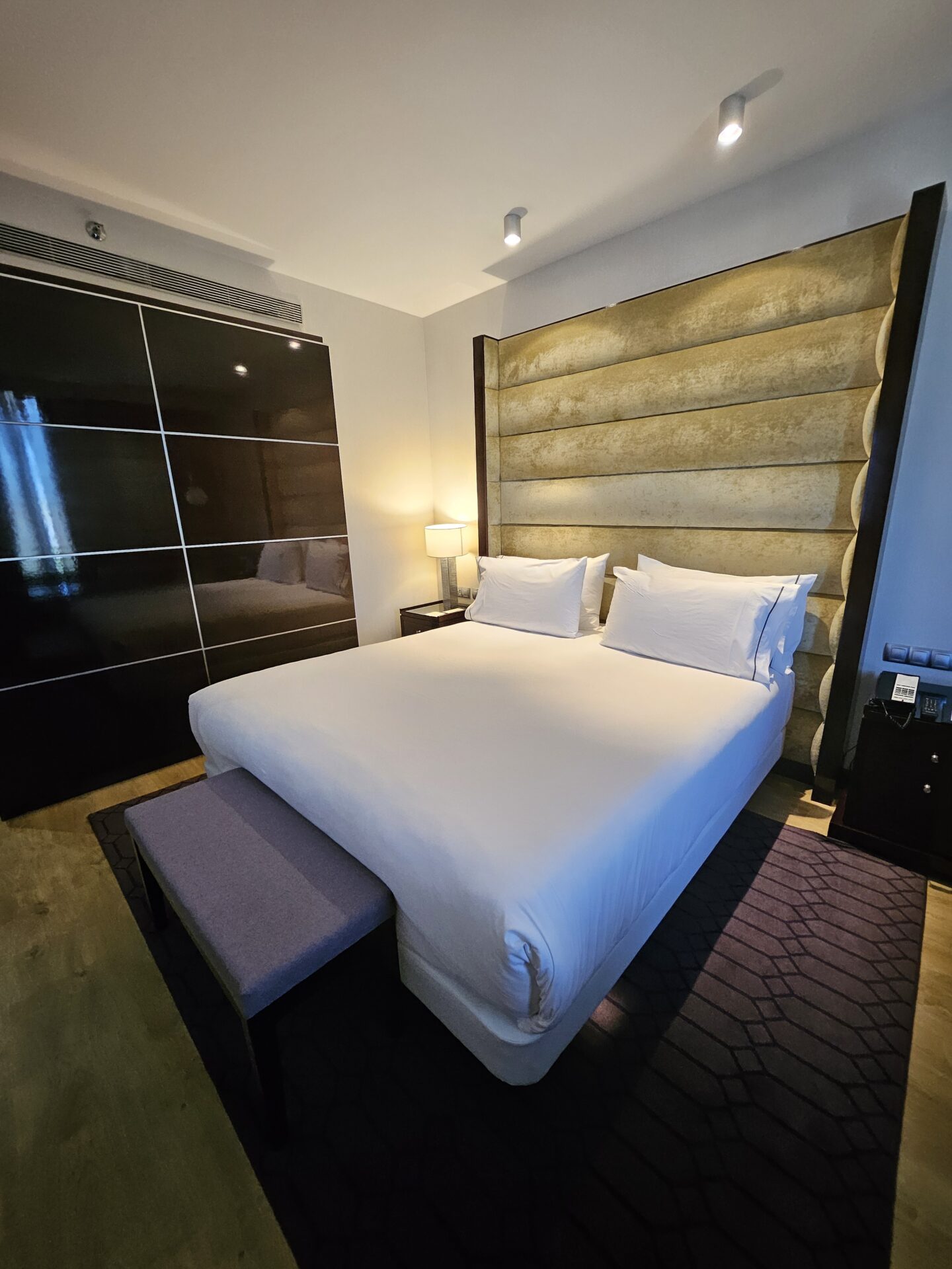 a bed with white sheets and a large headboard in a room