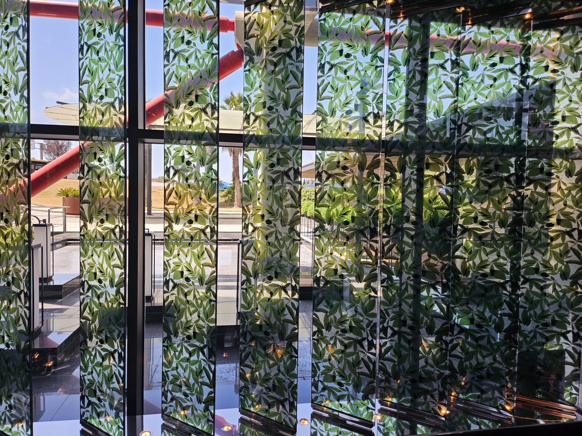 a glass wall with green leaves on it