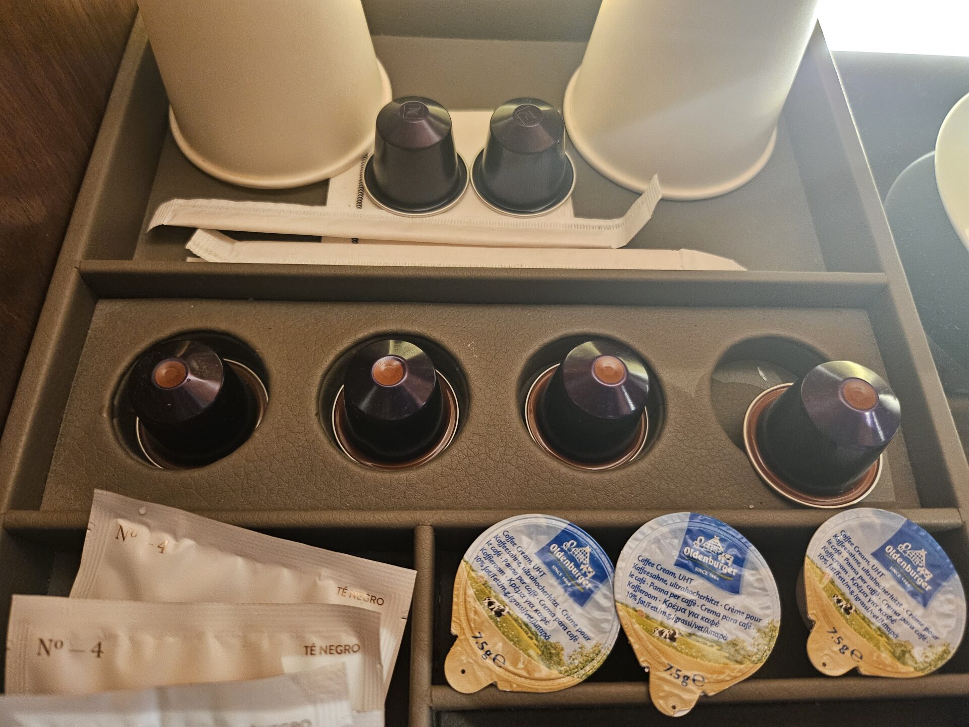 a tray with coffee capsules and condiments