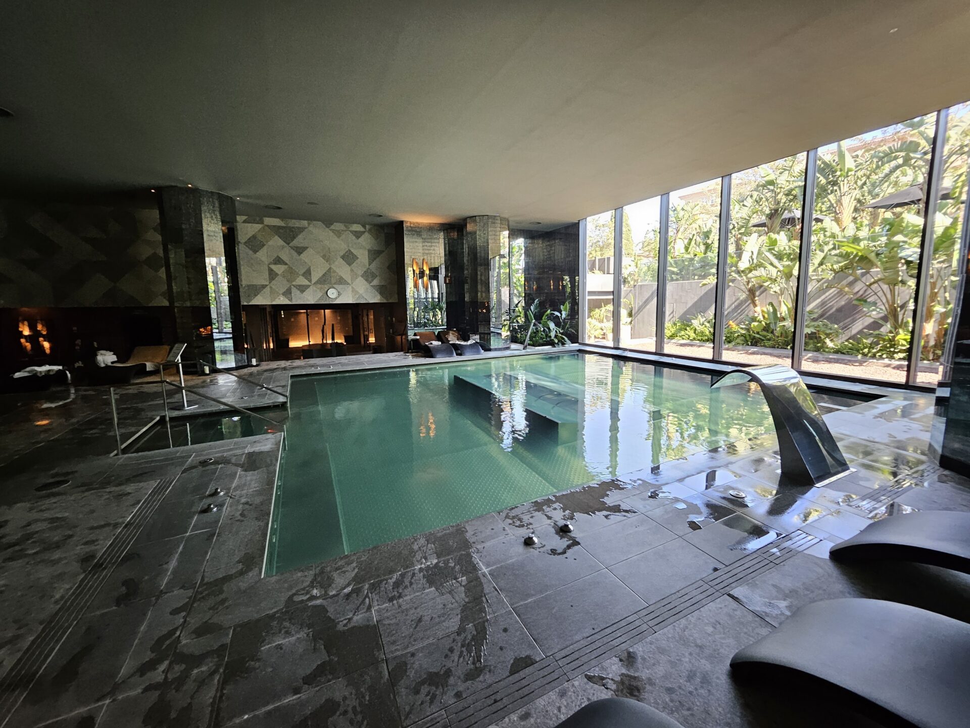 a large indoor pool with a fireplace and a large window