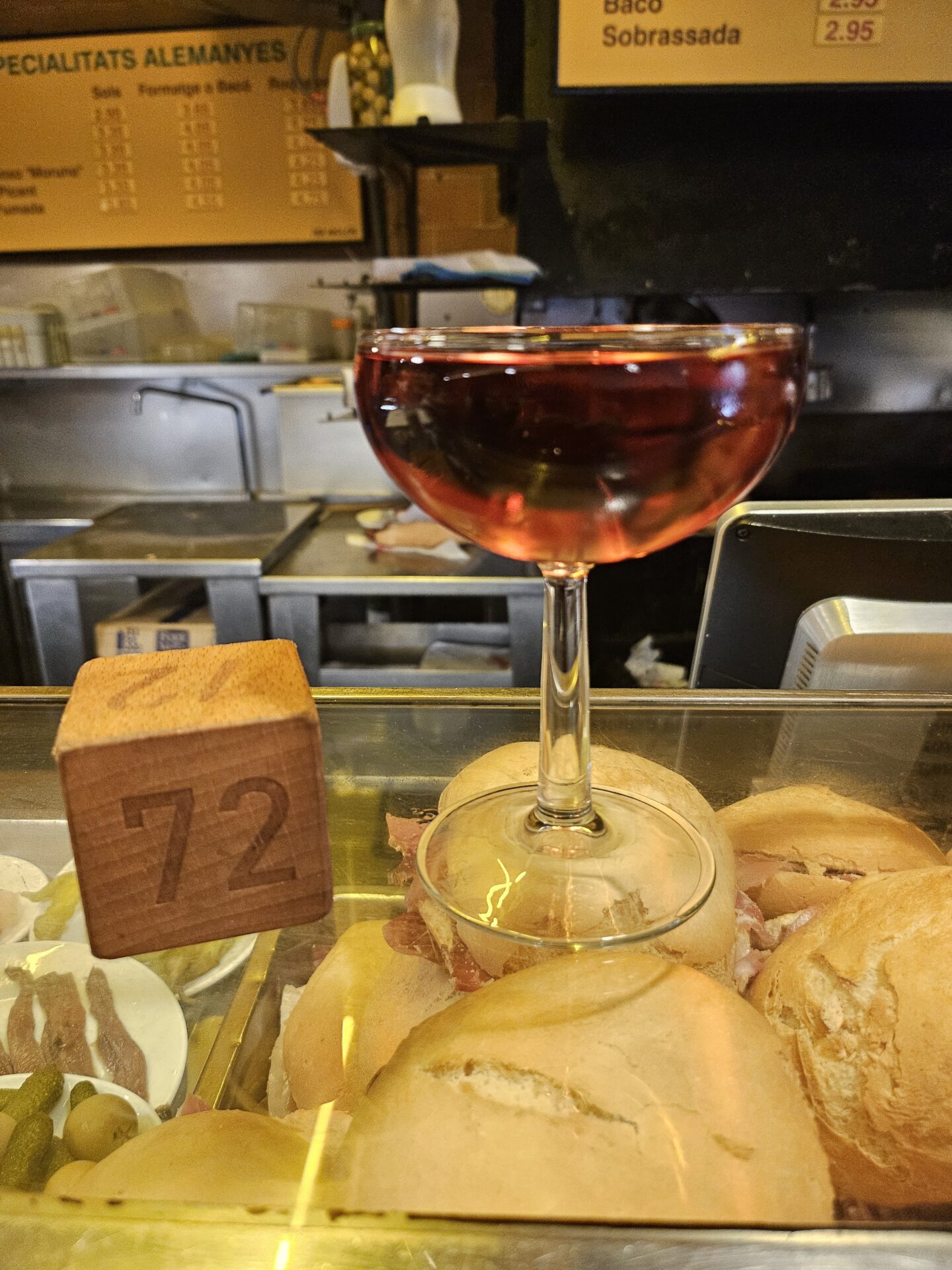 a glass of wine on a tray with bread rolls