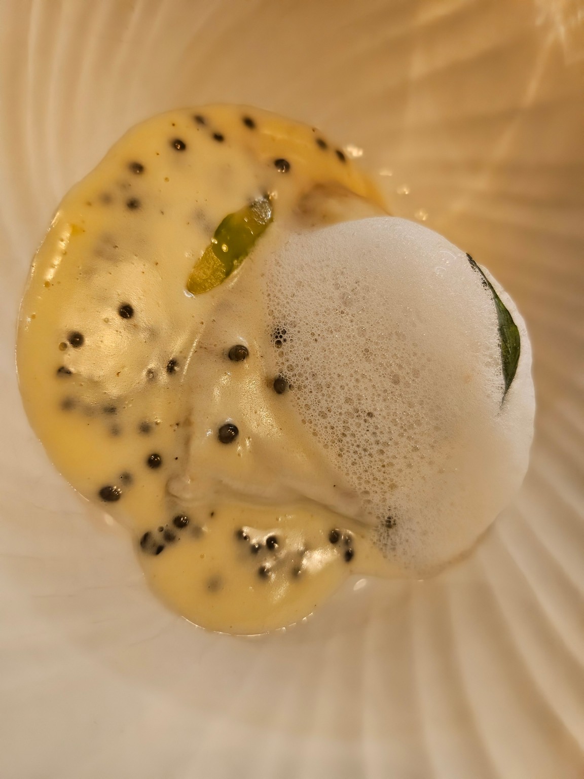 a white bowl with yellow liquid and black dots