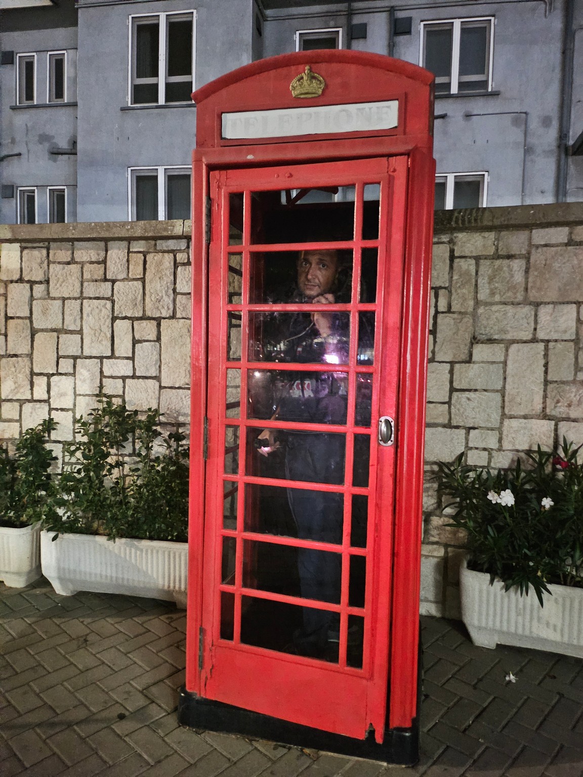 a person standing in a red telephone booth